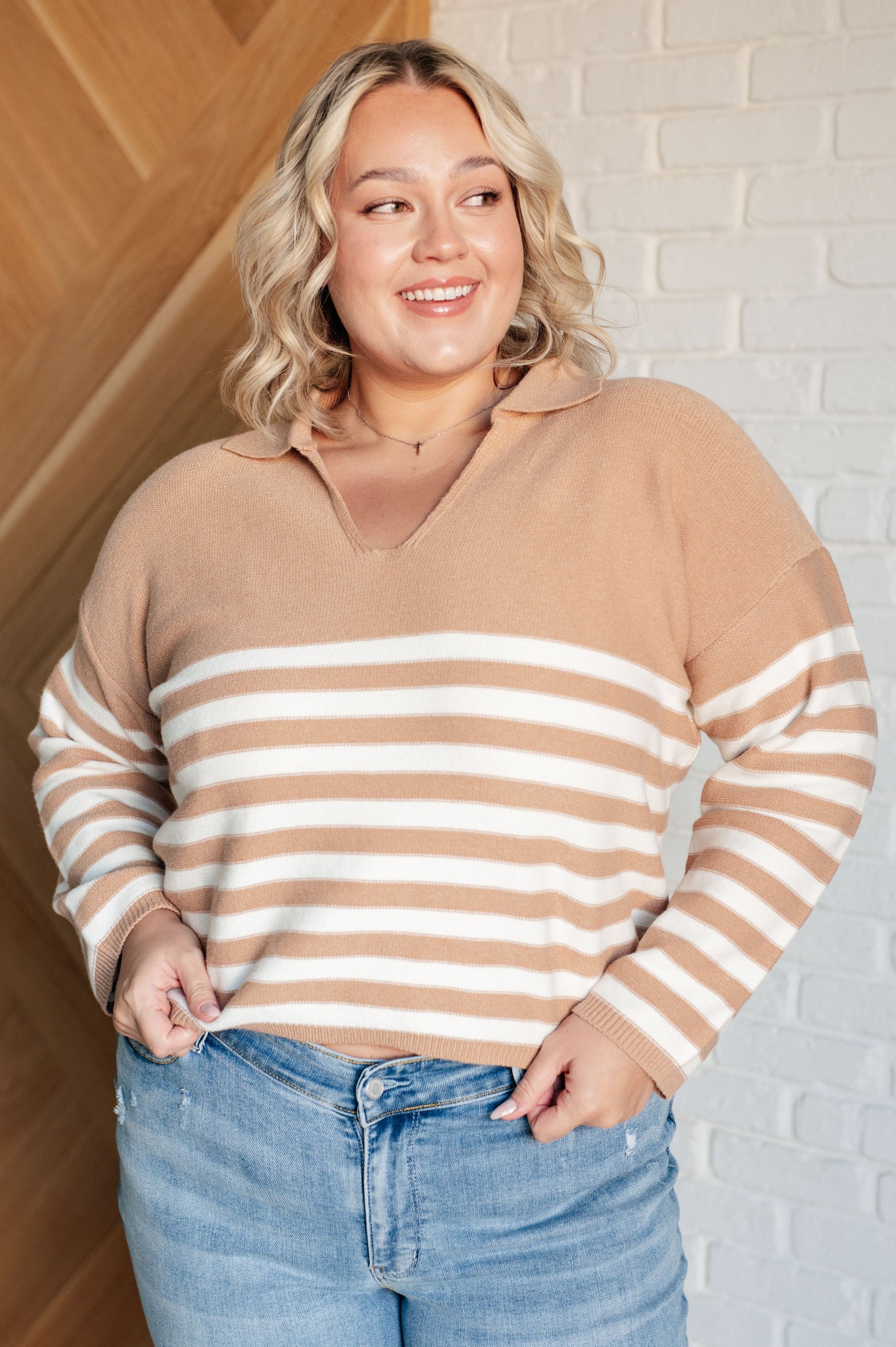 A striped midweight sweater knit in white and beige featuring a collared V-neckline, long sleeves, and a cropped length with a relaxed fit.