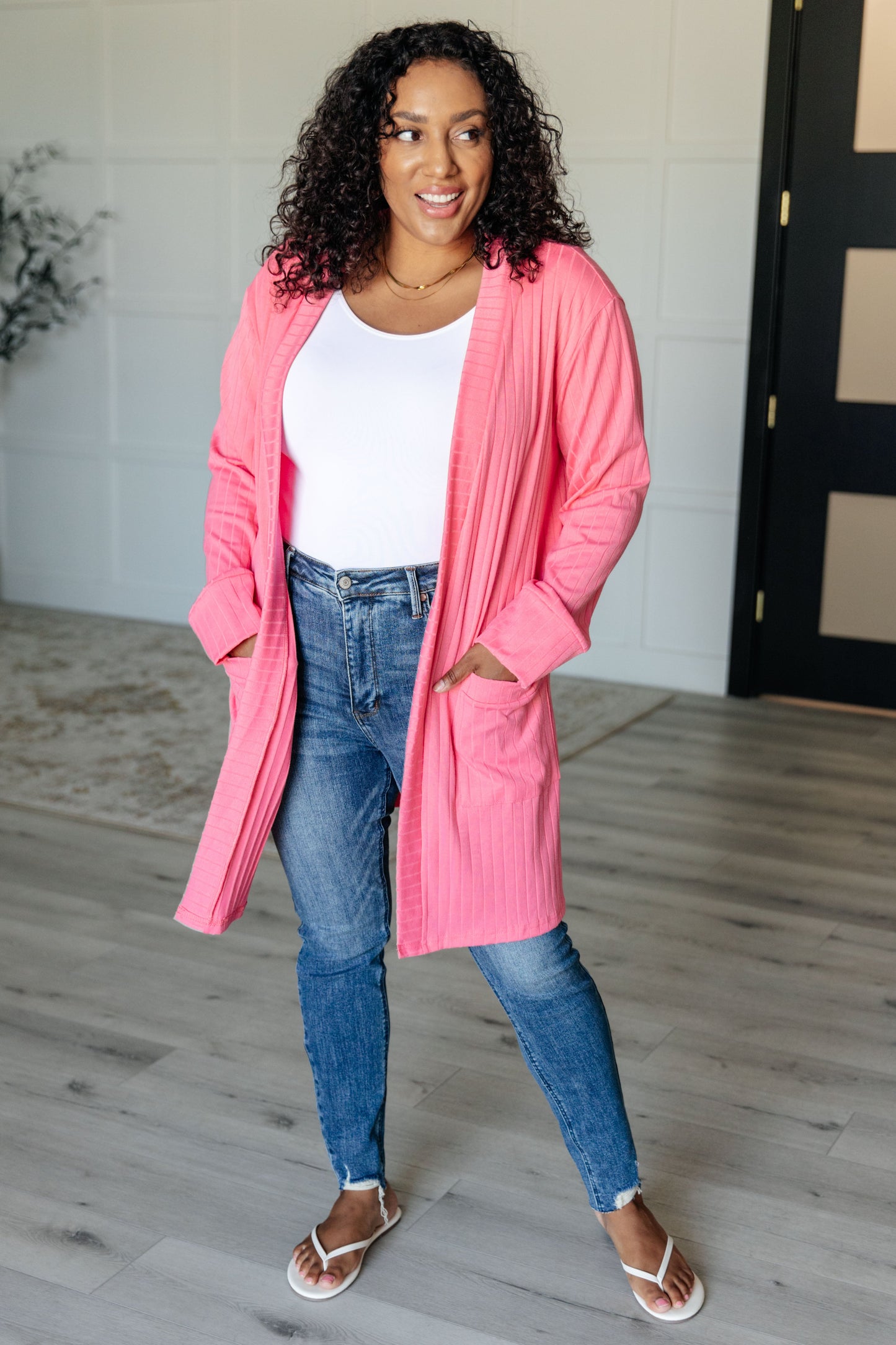 Pink ribbed knit cardigan with functional patch pockets, exaggerated sleeve cuffs, long sleeves, and an open front.