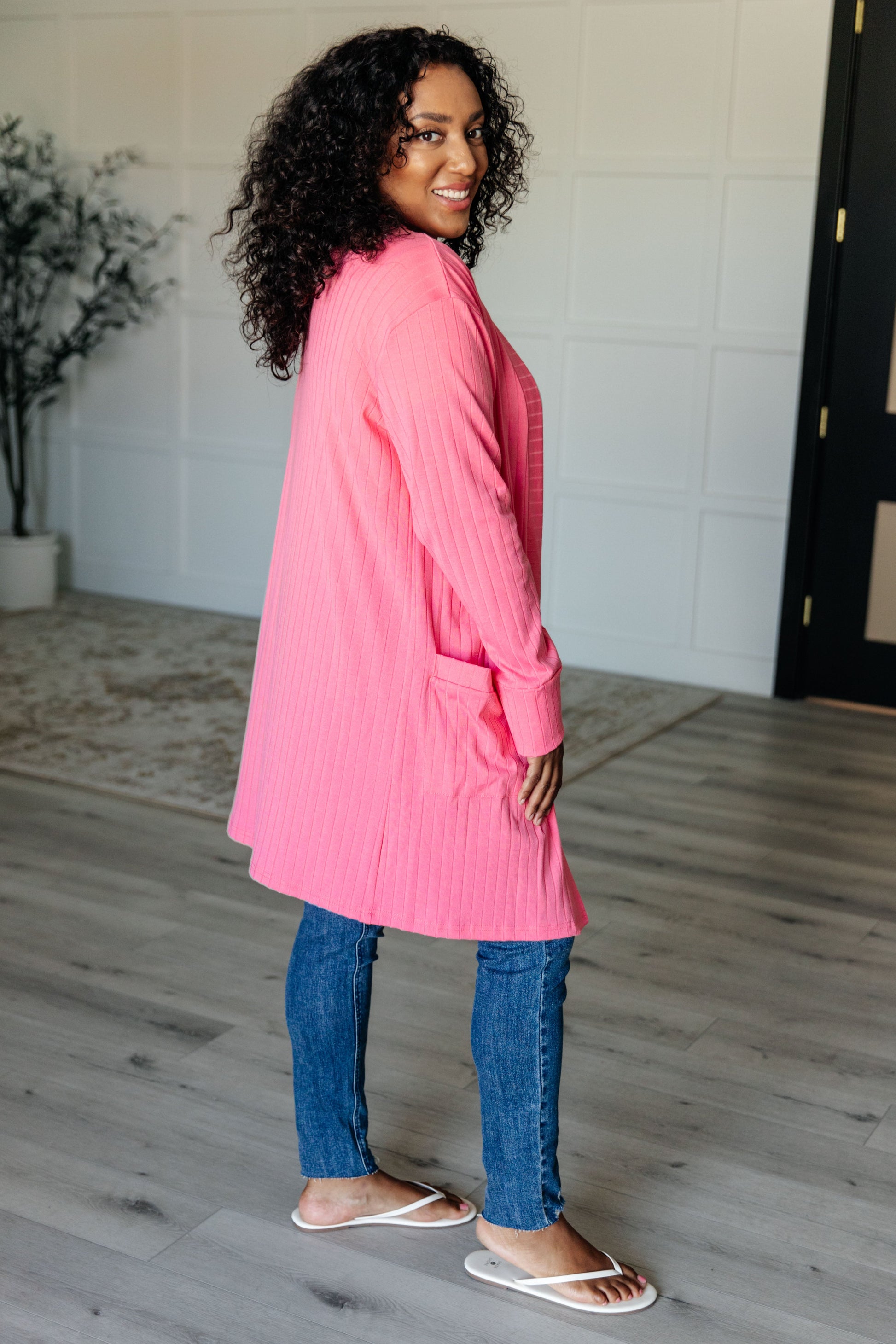 Pink ribbed knit cardigan with functional patch pockets, exaggerated sleeve cuffs, long sleeves, and an open front.