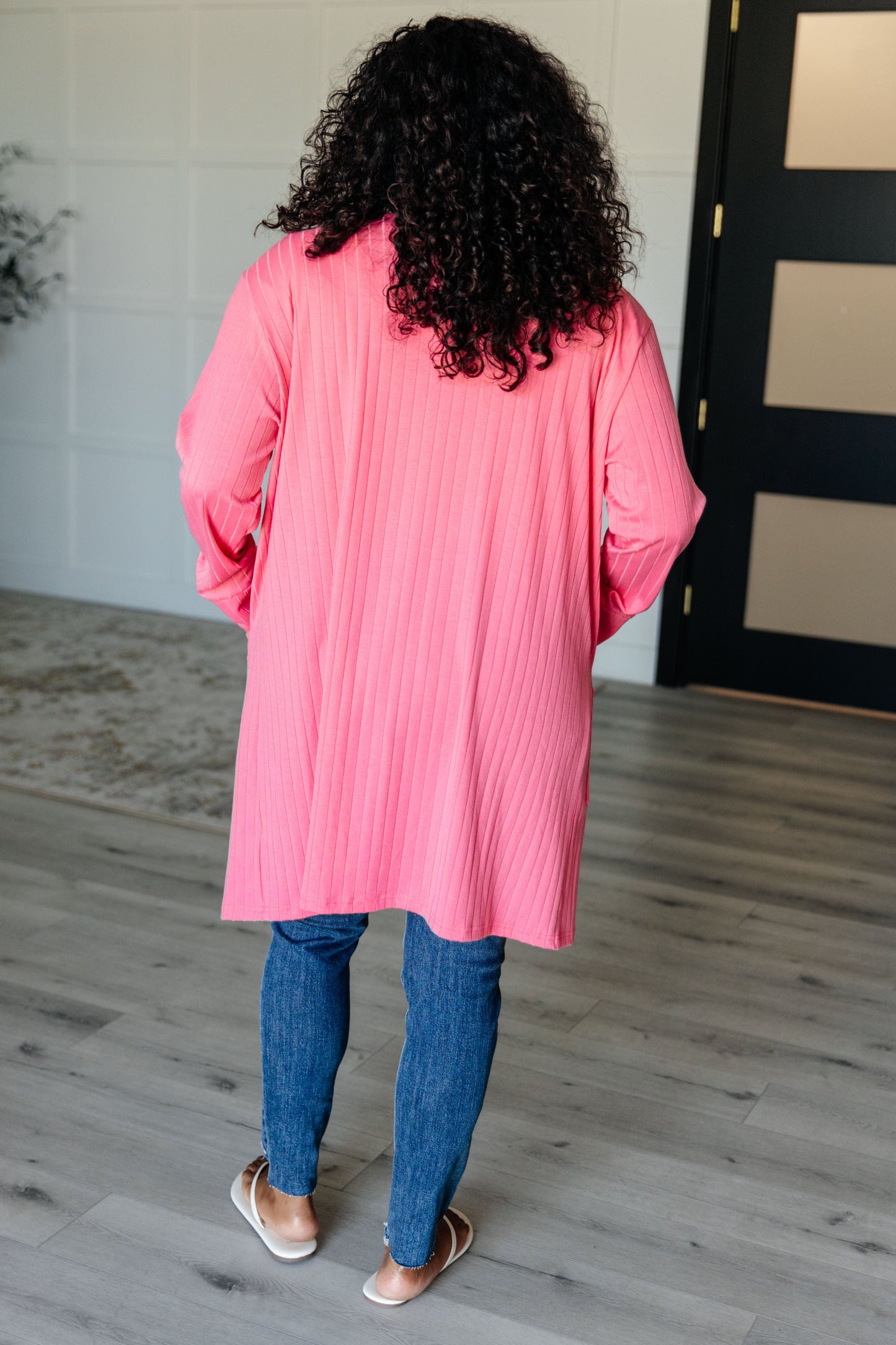 Pink ribbed knit cardigan with functional patch pockets, exaggerated sleeve cuffs, long sleeves, and an open front.