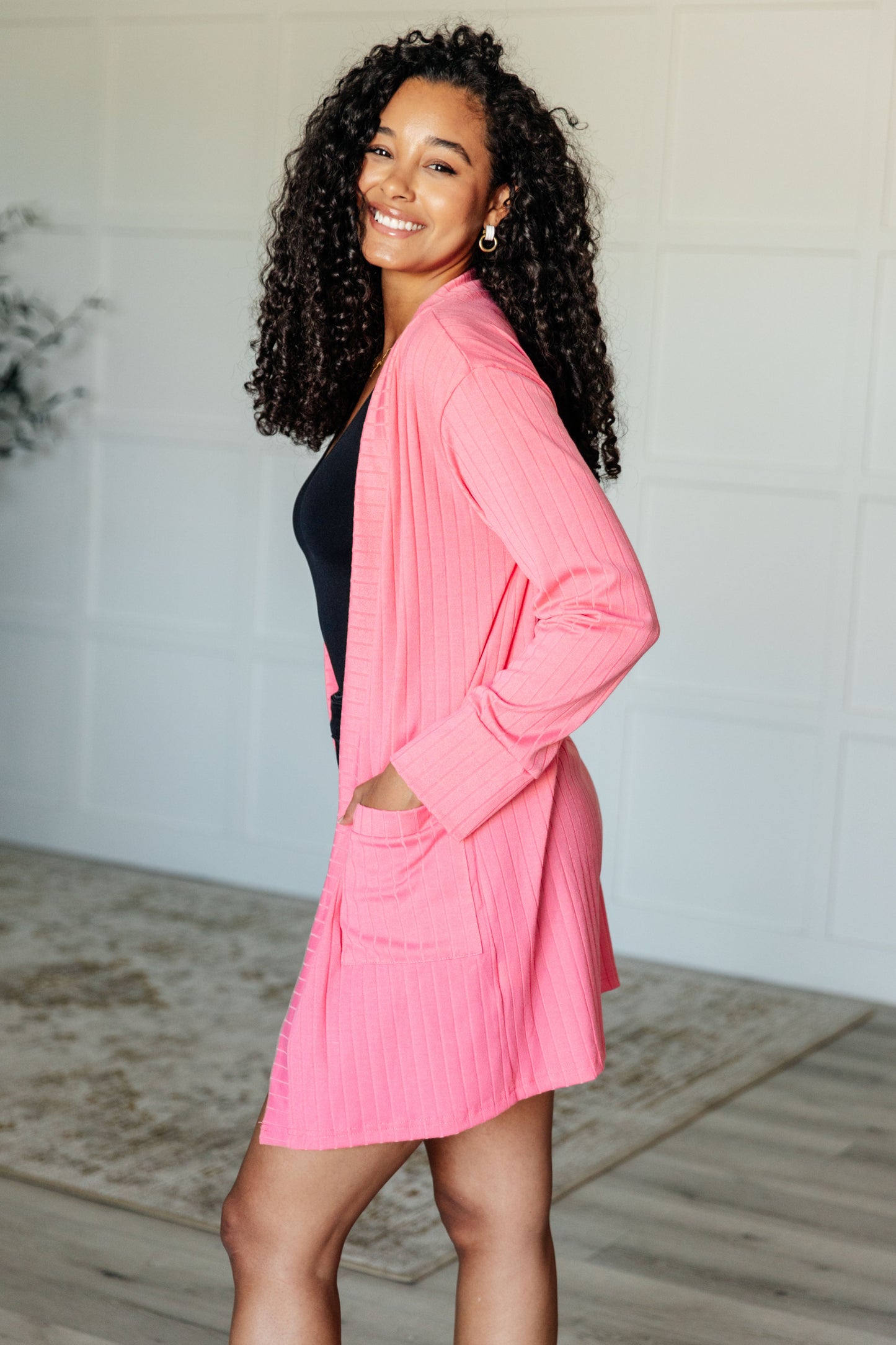 Pink ribbed knit cardigan with functional patch pockets, exaggerated sleeve cuffs, long sleeves, and an open front.