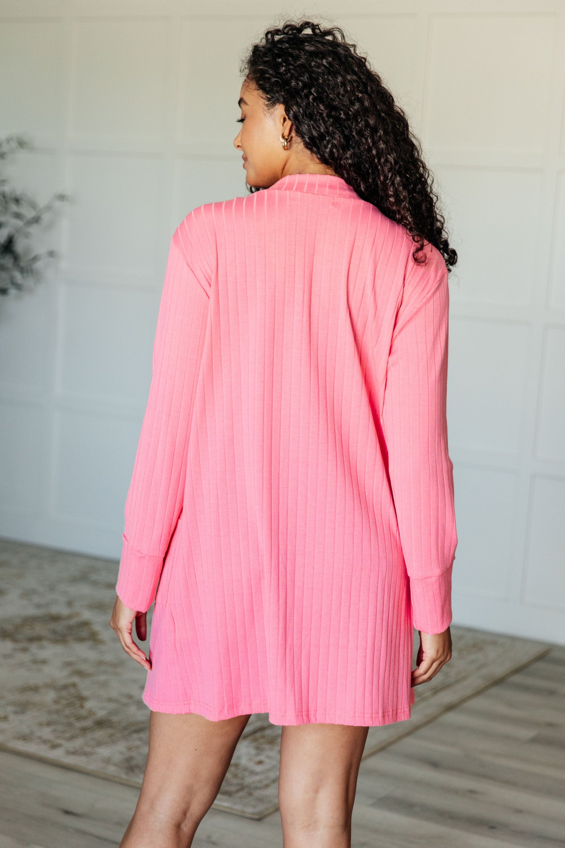 Pink ribbed knit cardigan with functional patch pockets, exaggerated sleeve cuffs, long sleeves, and an open front.