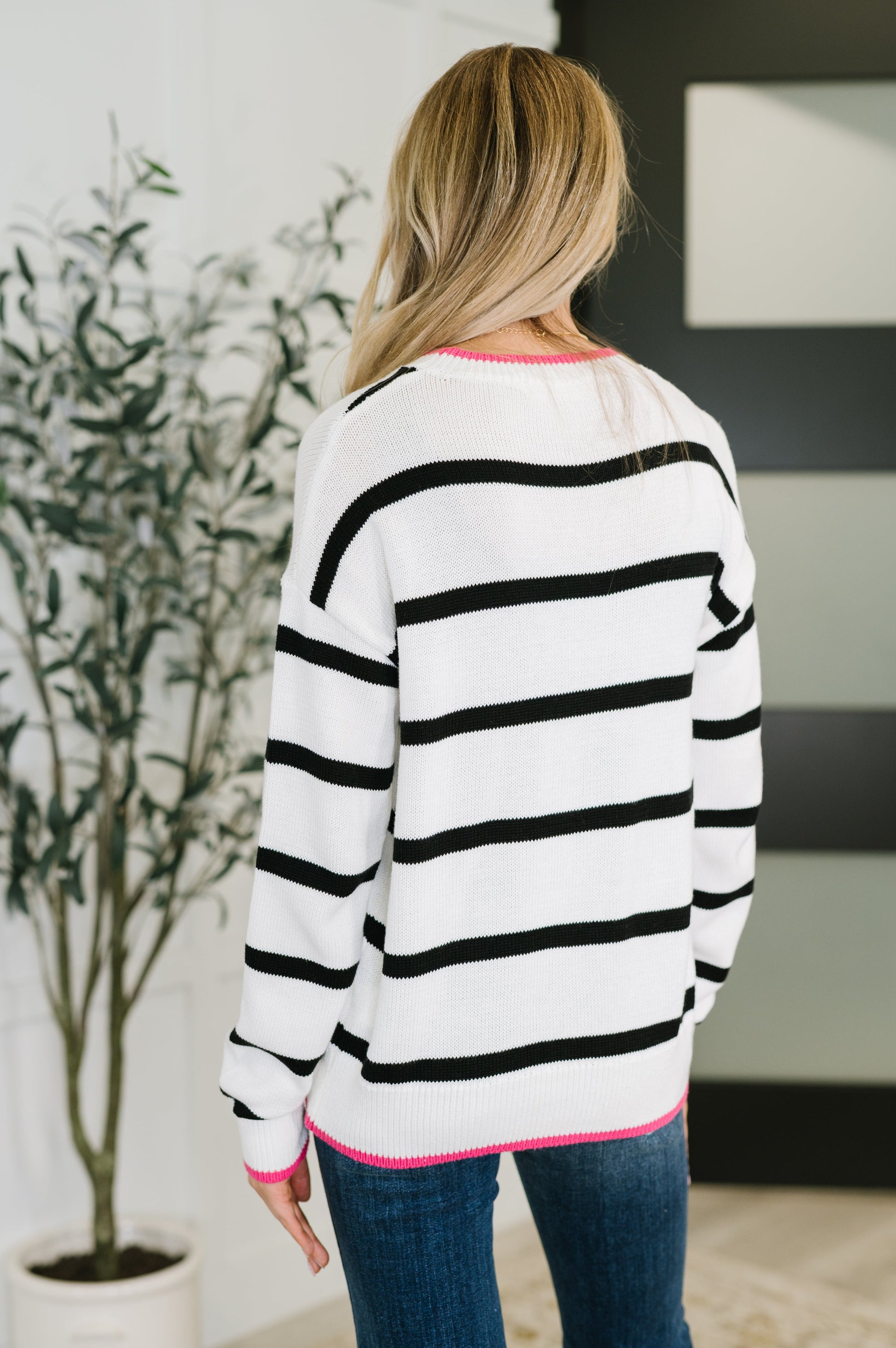 Back of Daphne Striped Sweater with horizontal black-and-white stripes and pink hemline trim.