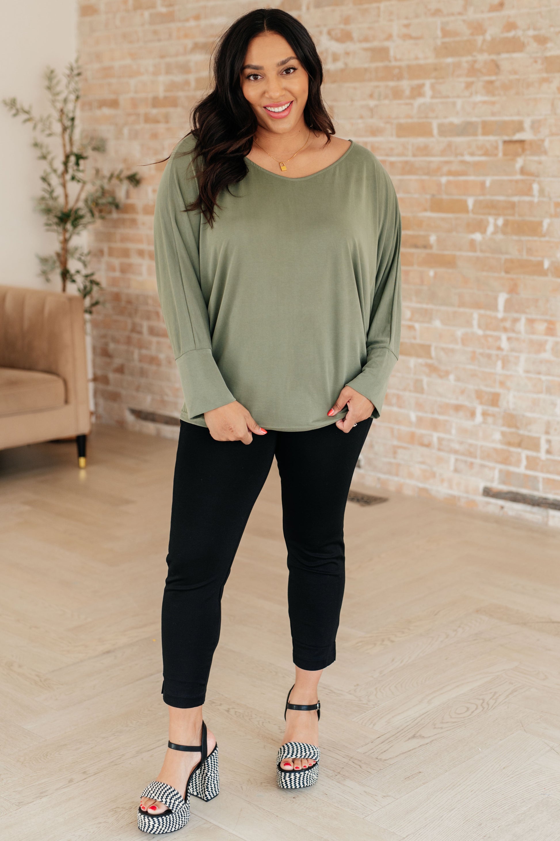 Plus size model full body wearing Micah Sage Long Sleeve Top with exaggerated sleeve cuffs and dolman design