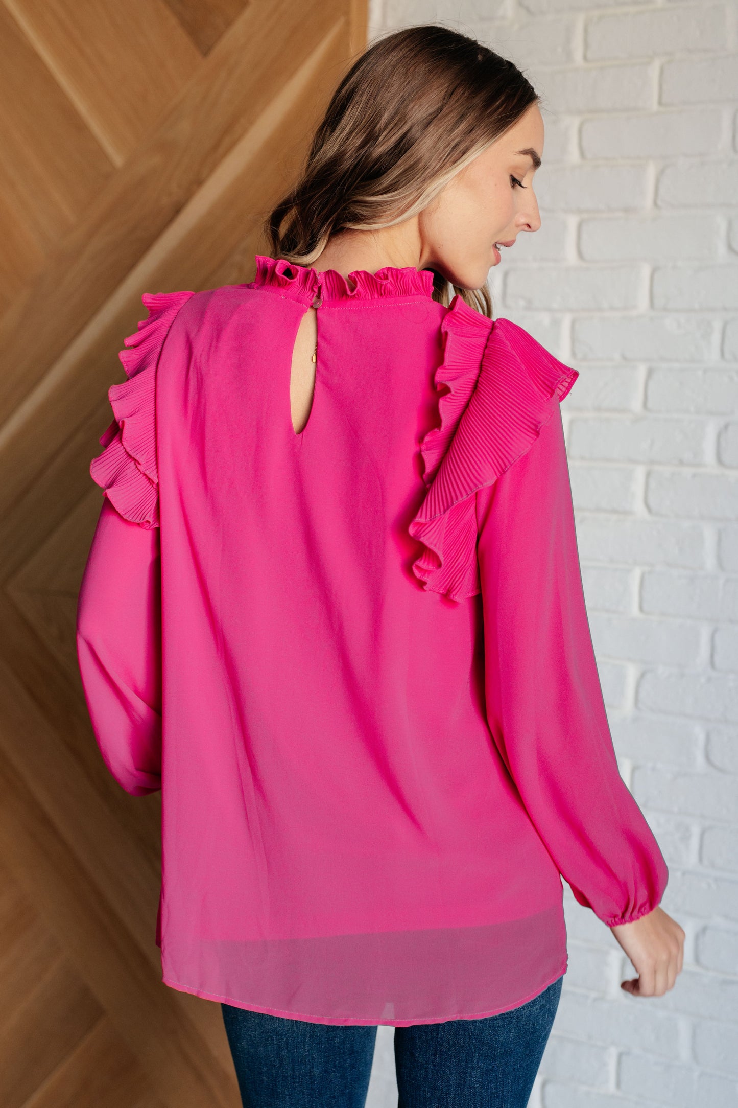 Soft Poly Crepe top in hot pink with mock neckline, ruffle details, long balloon sleeves with elastic cuffs, and keyhole button closure. Lined bodice.