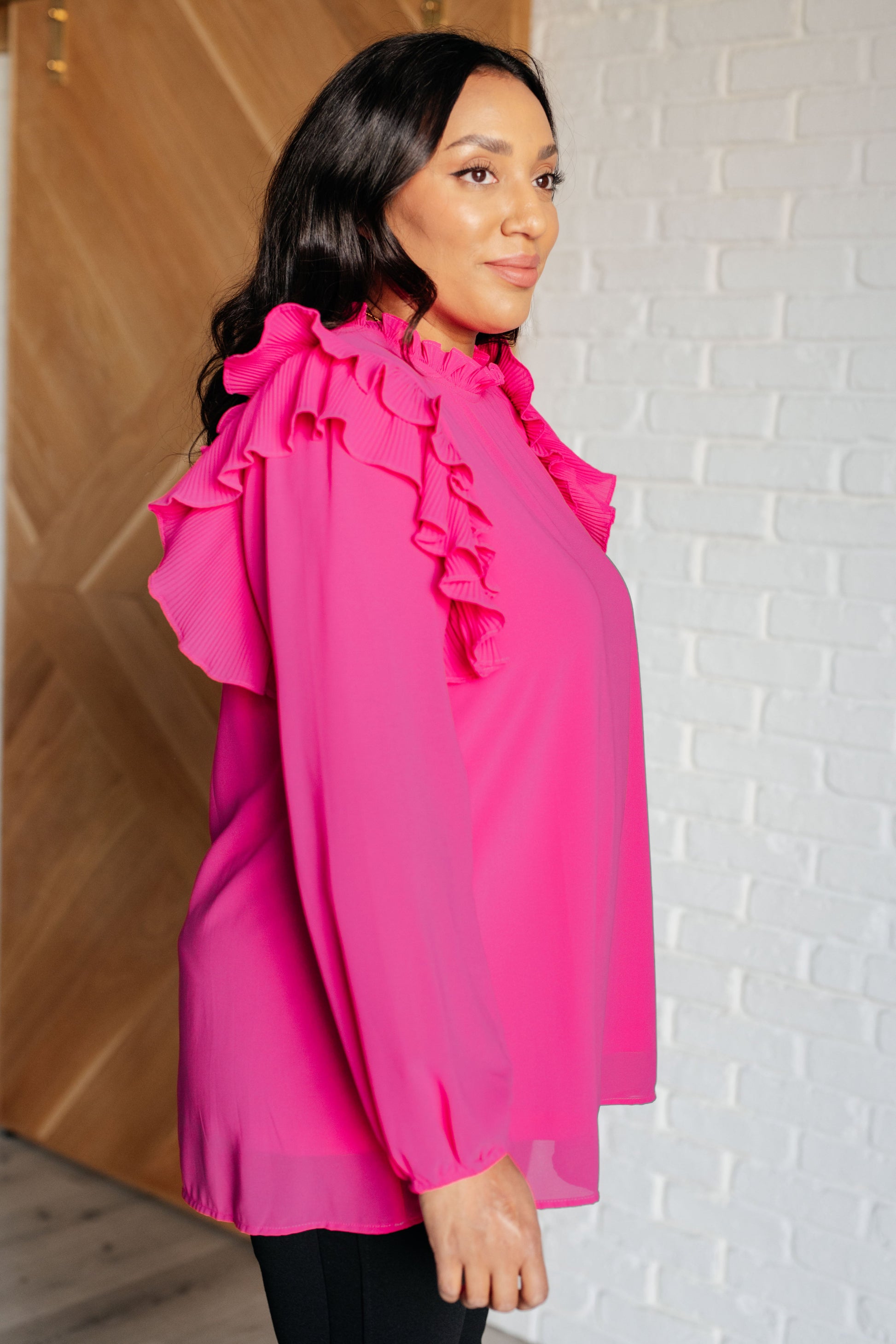 Soft Poly Crepe top in hot pink with mock neckline, ruffle details, long balloon sleeves with elastic cuffs, and keyhole button closure. Lined bodice.