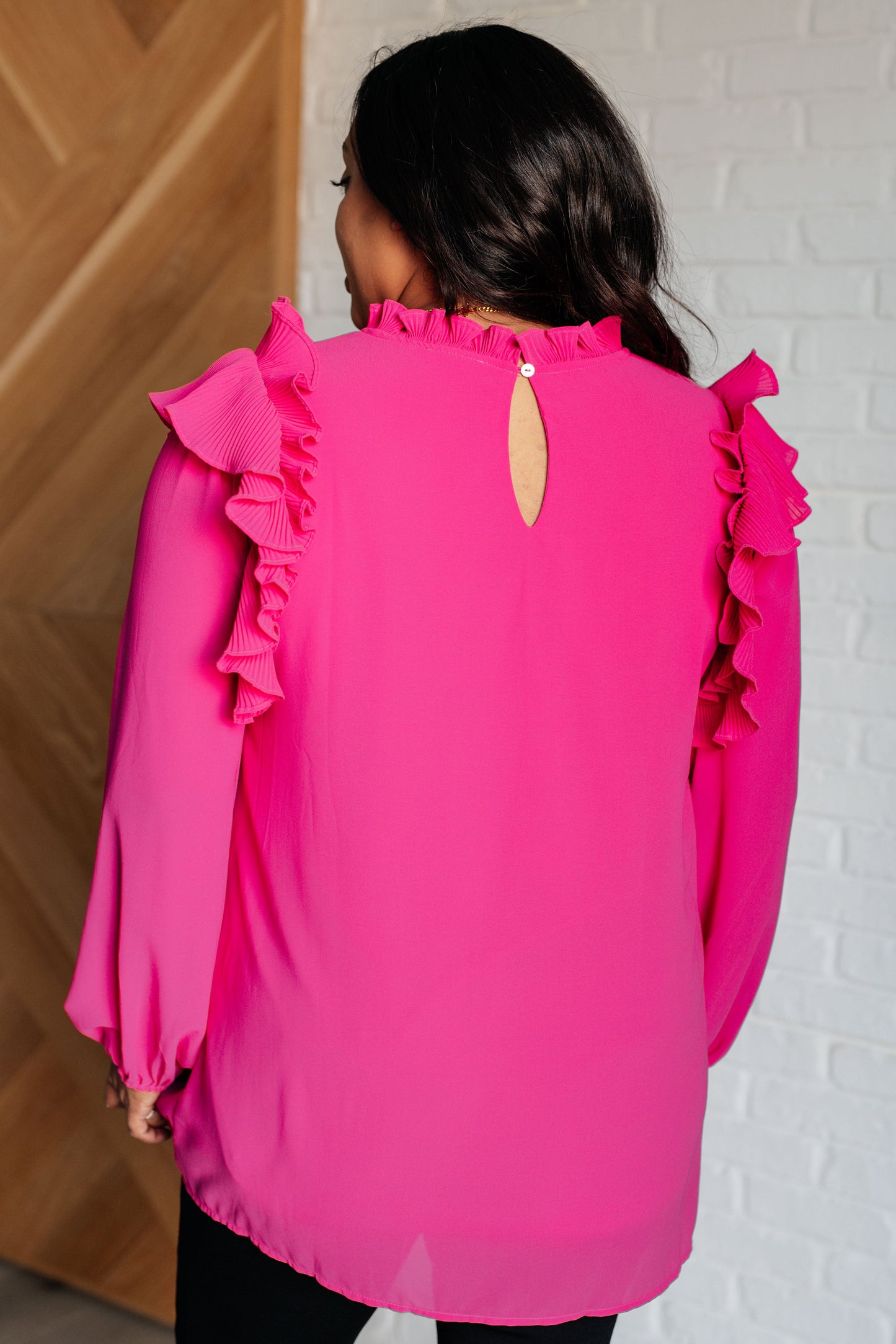 Soft Poly Crepe top in hot pink with mock neckline, ruffle details, long balloon sleeves with elastic cuffs, and keyhole button closure. Lined bodice.