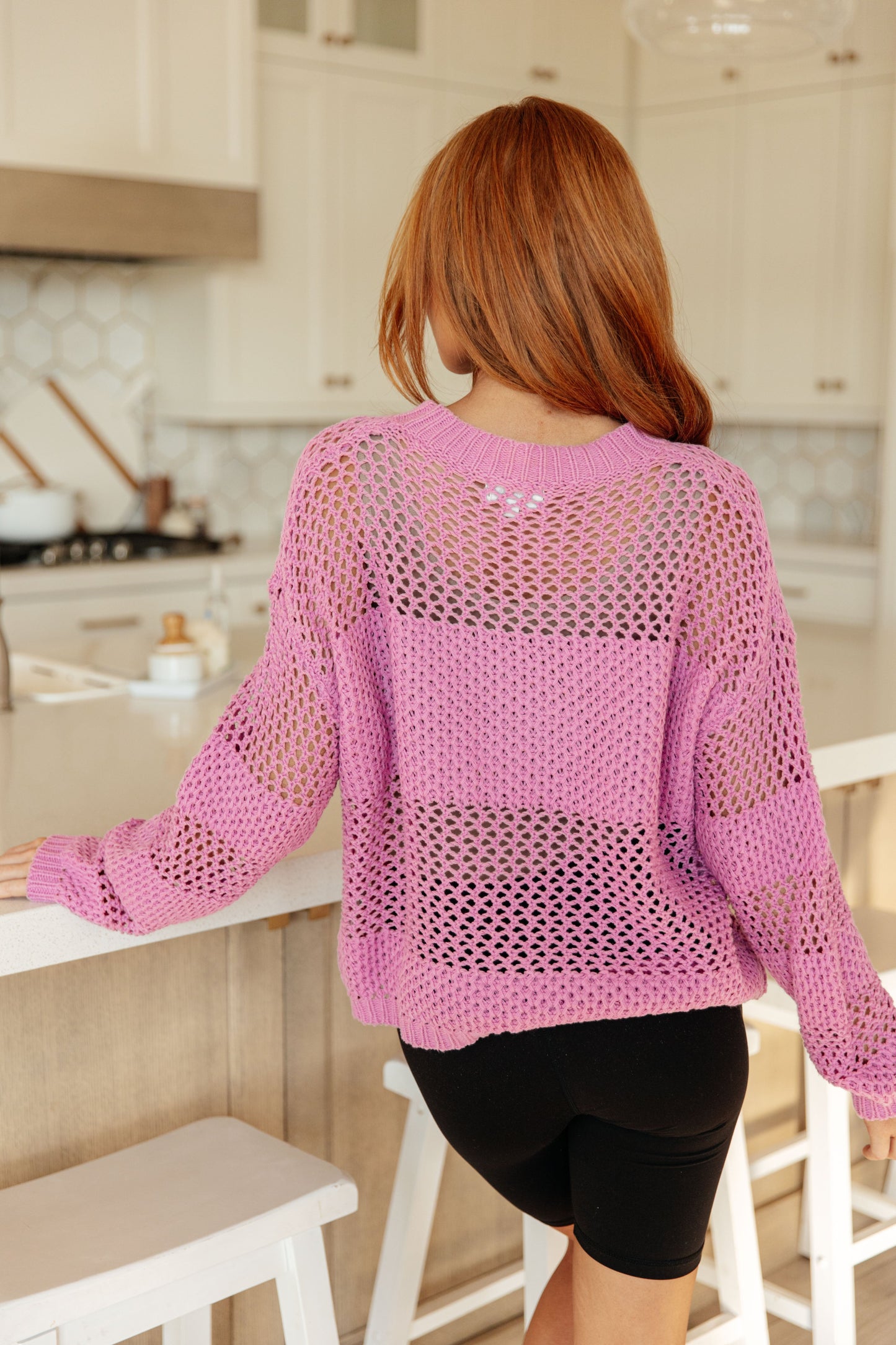Back view of the Leia Pink Open Knit Sweater highlighting its see-through loose-knit texture and bold block stripe design.