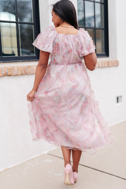 Back view of Malia Flutter Sleeve Dress in pink floral tulle with flowy silhouette and flutter sleeves