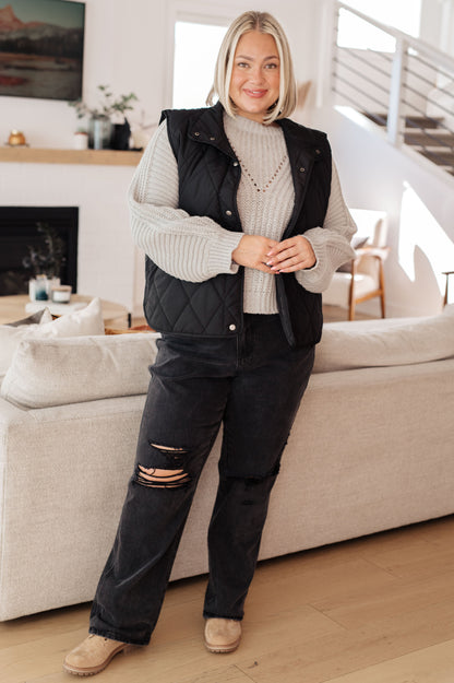 Plus size model layering Hattie Balloon Sleeve Sweater with a black quilted vest and distressed jeans.