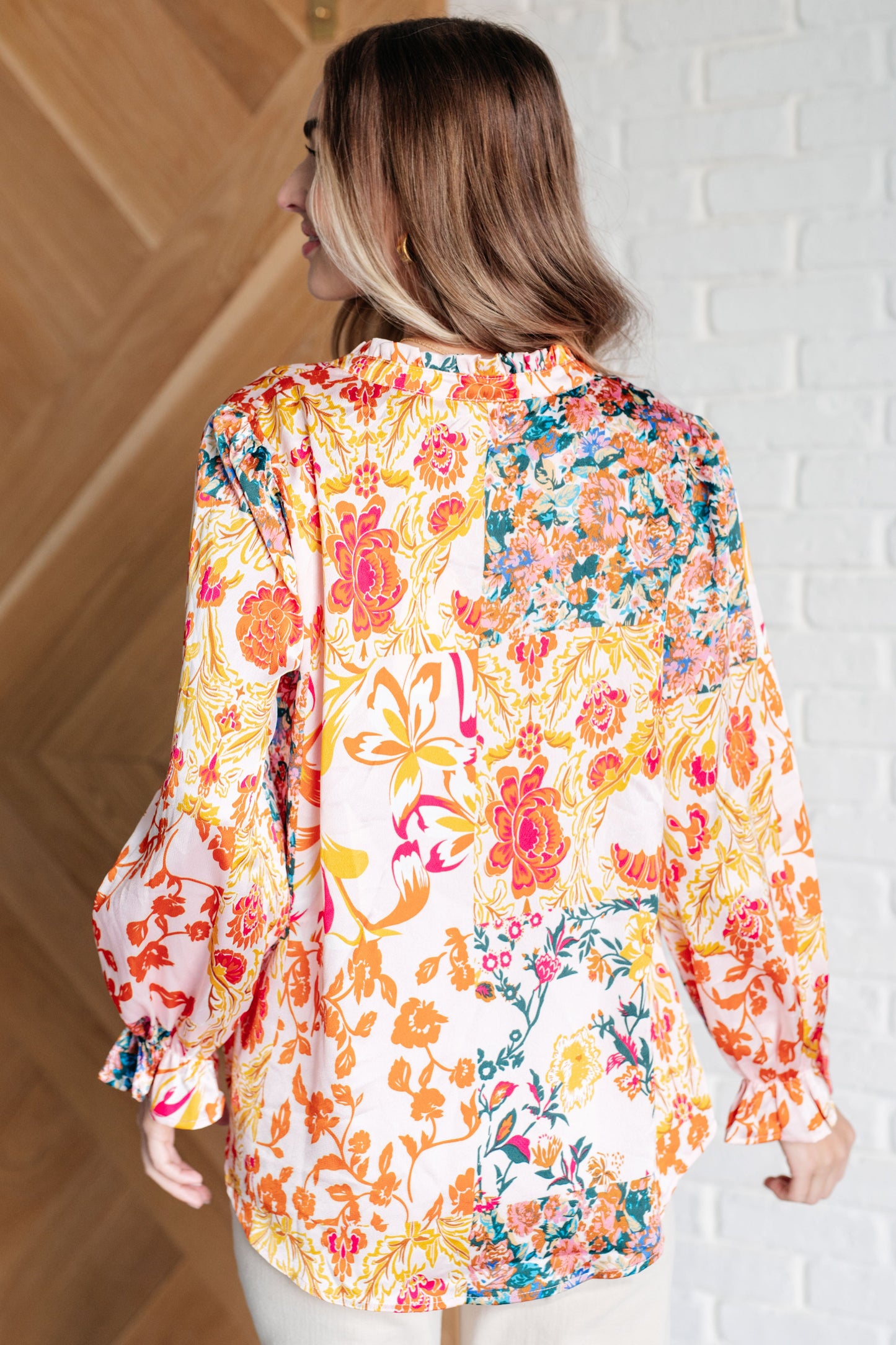 Floral poly satin blouse with a frilled V-neckline, neck tie, long poet sleeves with frilled elastic cuffs, and a curved hemline.