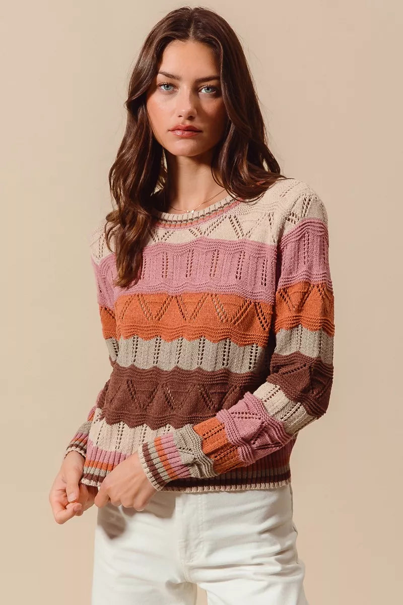 Model wearing Nina Multi Color Wavy Stripe Sweater Top with long sleeves and round neckline.