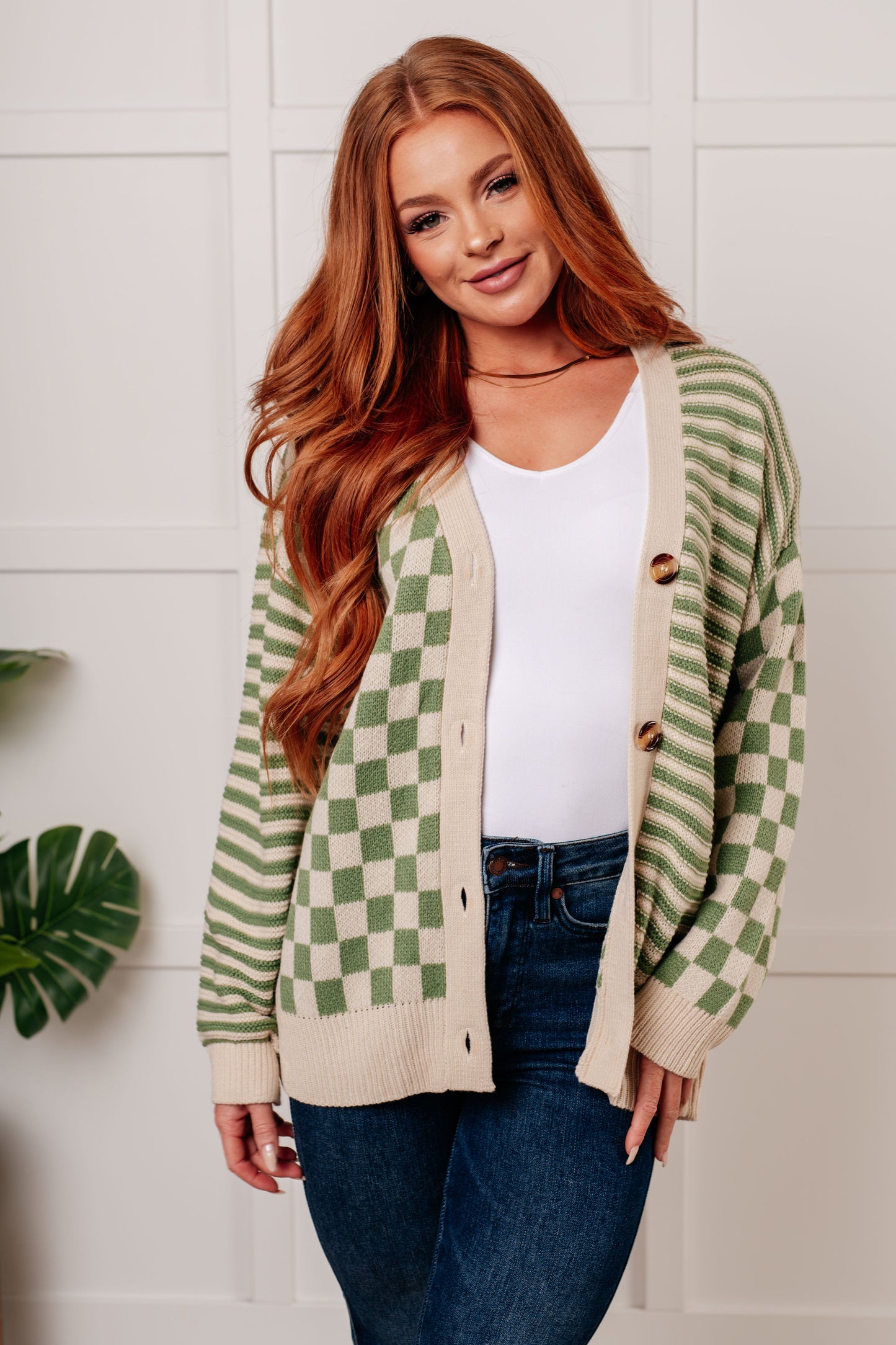 Women's green and beige cardigan featuring a checkered and striped pattern, V-neckline, and long sleeves. Designed with button closures, banded ribbed cuffs, and a ribbed hemline.