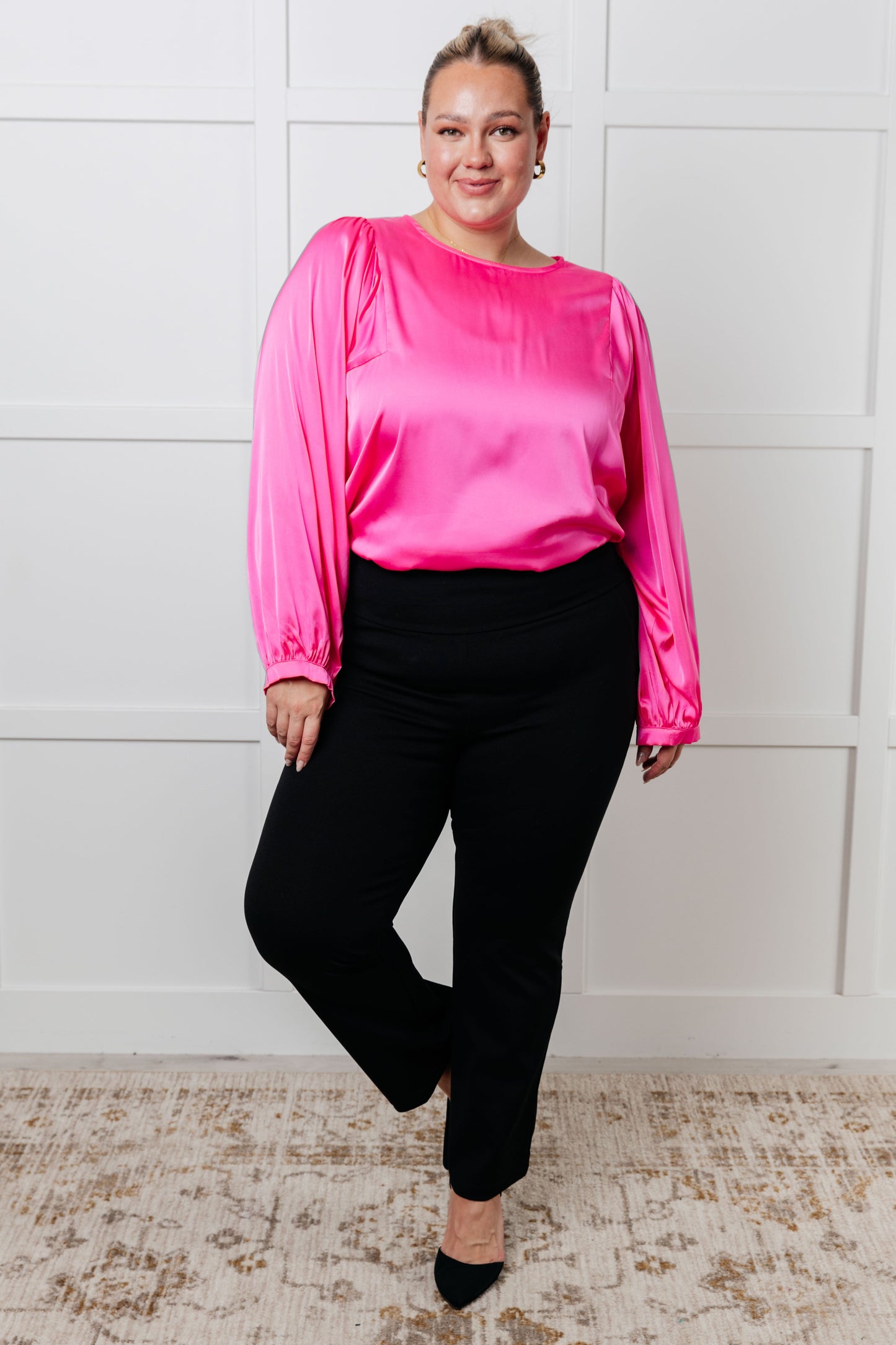 Pink  satin blouse with round neckline and long puff sleeves. Features banded sleeve cuffs and a back keyhole button closure.