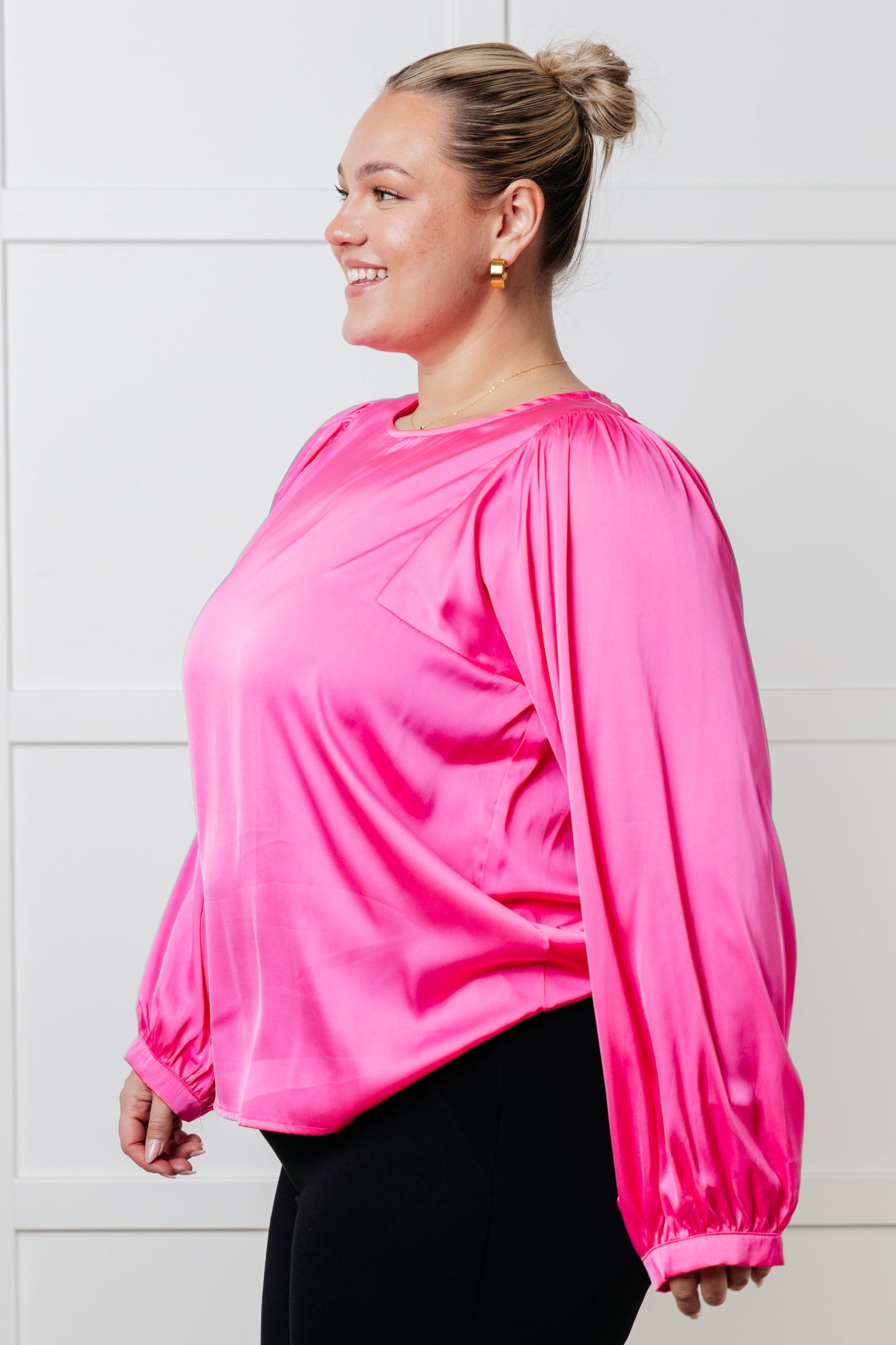 Pink poly satin blouse with round neckline and long puff sleeves. Features banded sleeve cuffs and a back keyhole button closure.