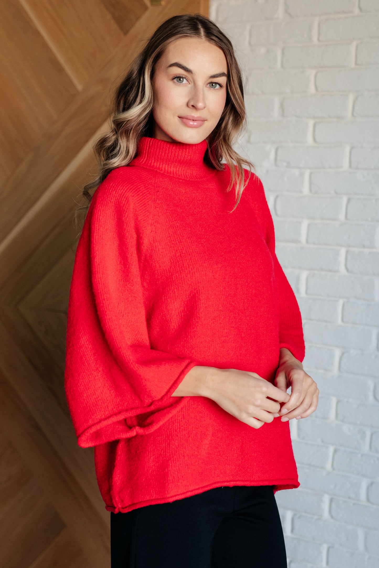 Women's turtleneck sweater in red-orange sweater knit, featuring wide raglan 3/4 length sleeves and a relaxed fit.