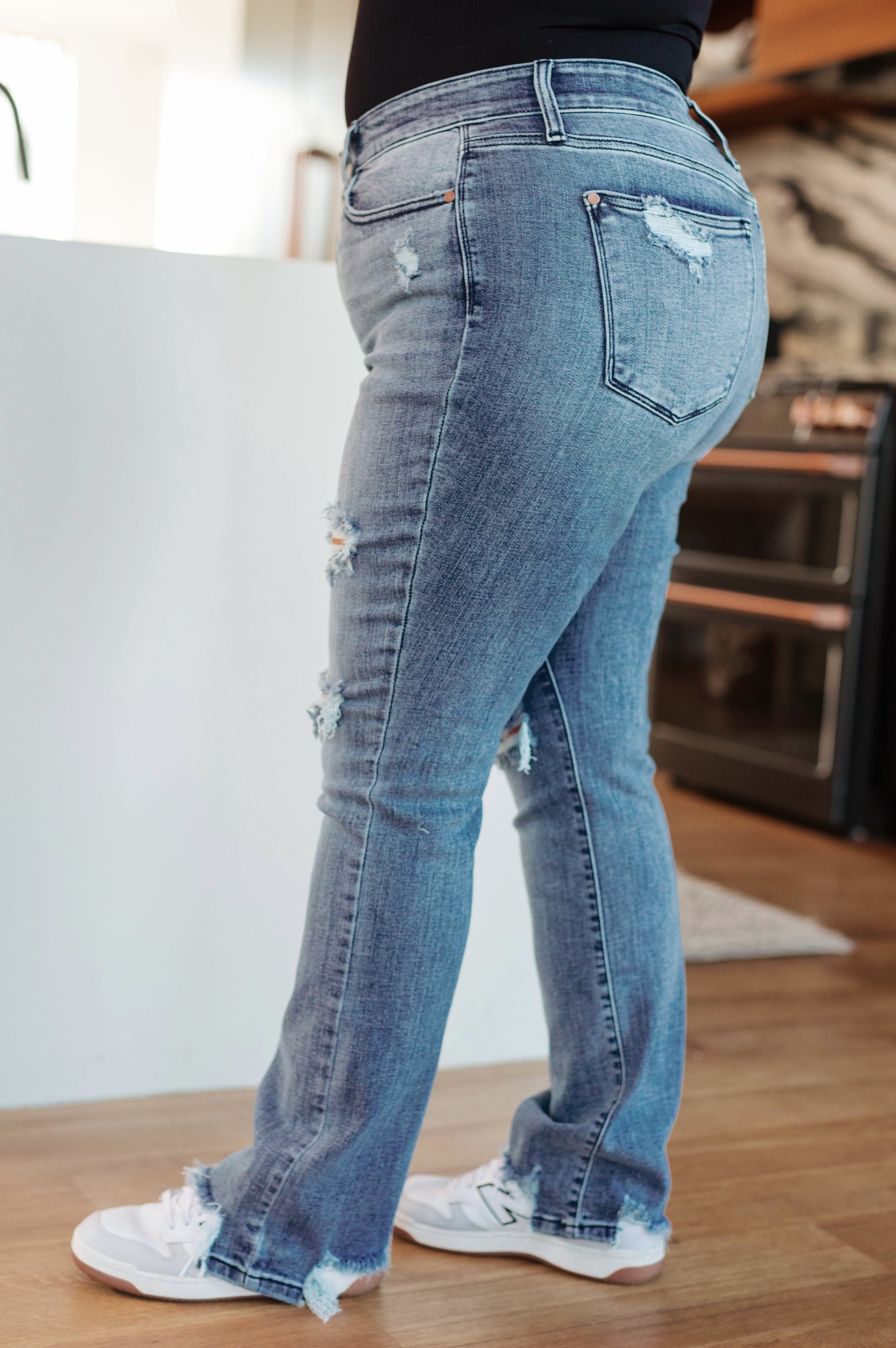 Medium wash mid-rise straight leg jeans with 4-way stretch for comfort. Features a five-pocket design, zipper fly, raw hem, and distressed details.