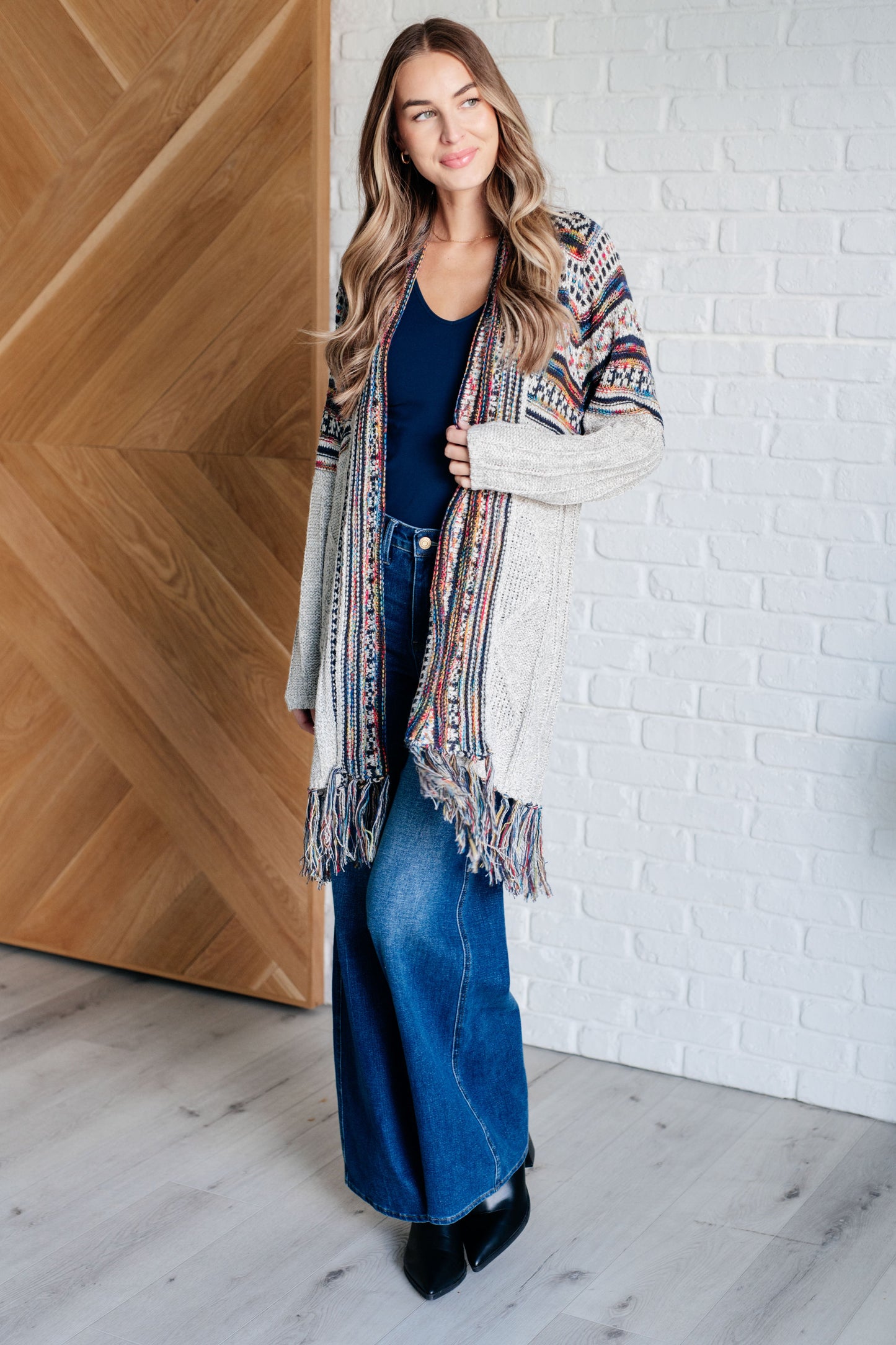 Women's cardigan with a shawl collar, geometric pattern, multi color, fringe trim, ribbed hem, and sweater knit fabric.