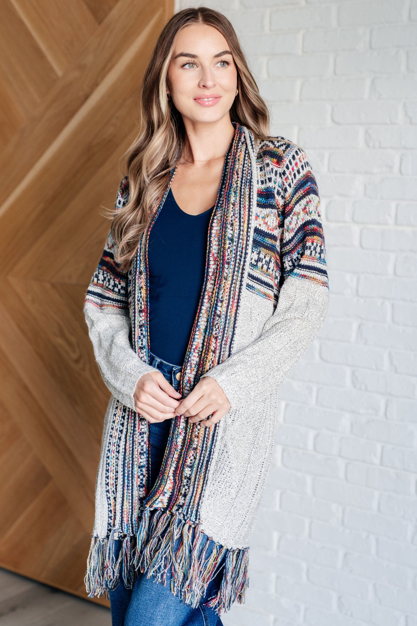 Women's cardigan with a shawl collar, geometric pattern, multi color, fringe trim, ribbed hem, and sweater knit fabric.