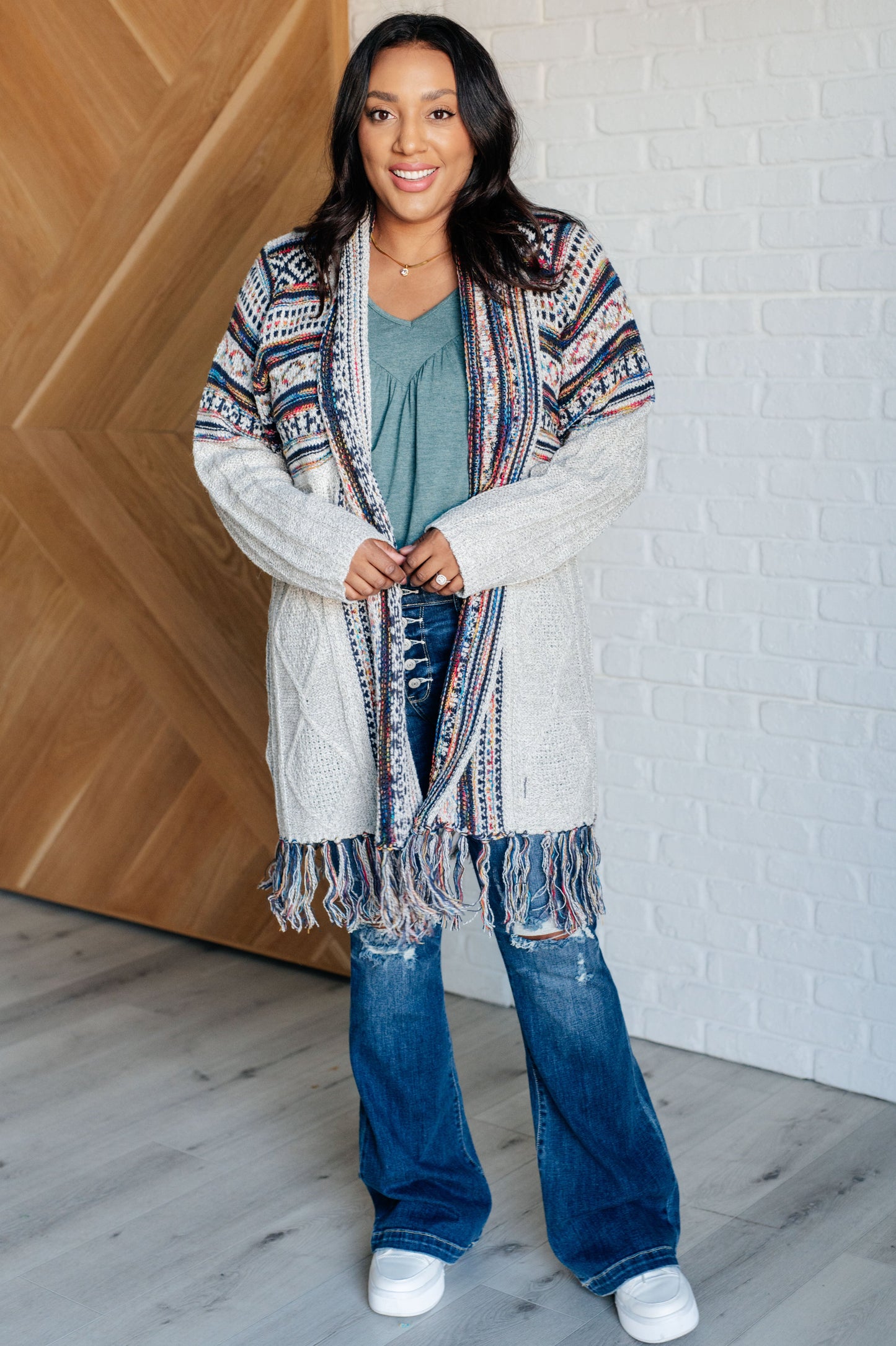 Women's cardigan with a shawl collar, geometric pattern, multi color, fringe trim, ribbed hem, and sweater knit fabric.