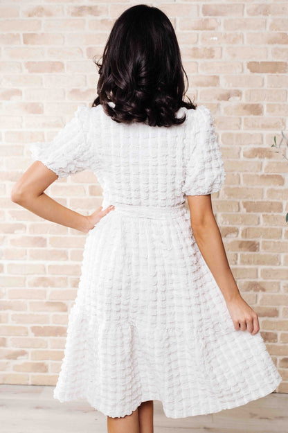 Back view of the Ivy Bubble Midi Dress in white with elastic waist, tie belt, and flowing tiered bubble knit skirt.