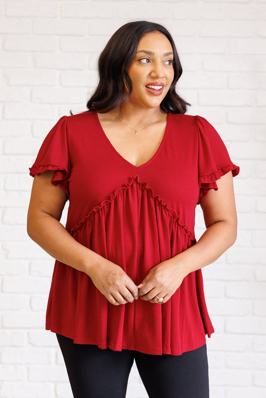 Plus size front view of Wesleigh V-Neck Ruffle Top in red with flutter sleeves and peplum silhouette.