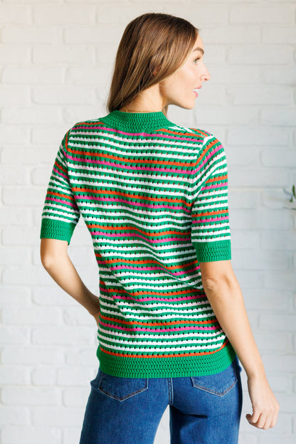 Back view of a model wearing the Sitarah Knit Striped Top in green with orange, white, and pink stripes, featuring a high-stretch sweater knit, round neckline, and half sleeves for a trendy and comfortable fit.