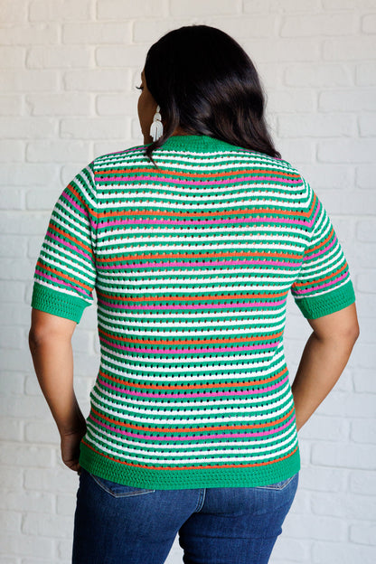 Back view of a plus size model wearing the Sitarah Knit Striped Top in green with orange, white, and pink stripes, featuring a high-stretch sweater knit, round neckline, and half sleeves for a trendy and comfortable fit.