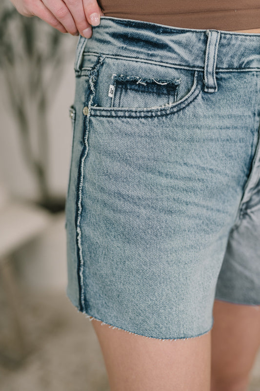 Close up of Paige High Waist Rigid Magic Cutoff Short by Judy Blue raw hem and distressed edges.