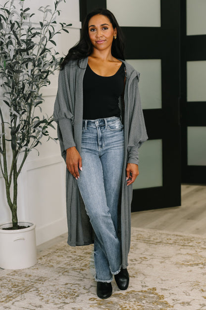 Model wearing Remington Hooded Cardigan in charcoal with open front and relaxed dolman sleeves.
