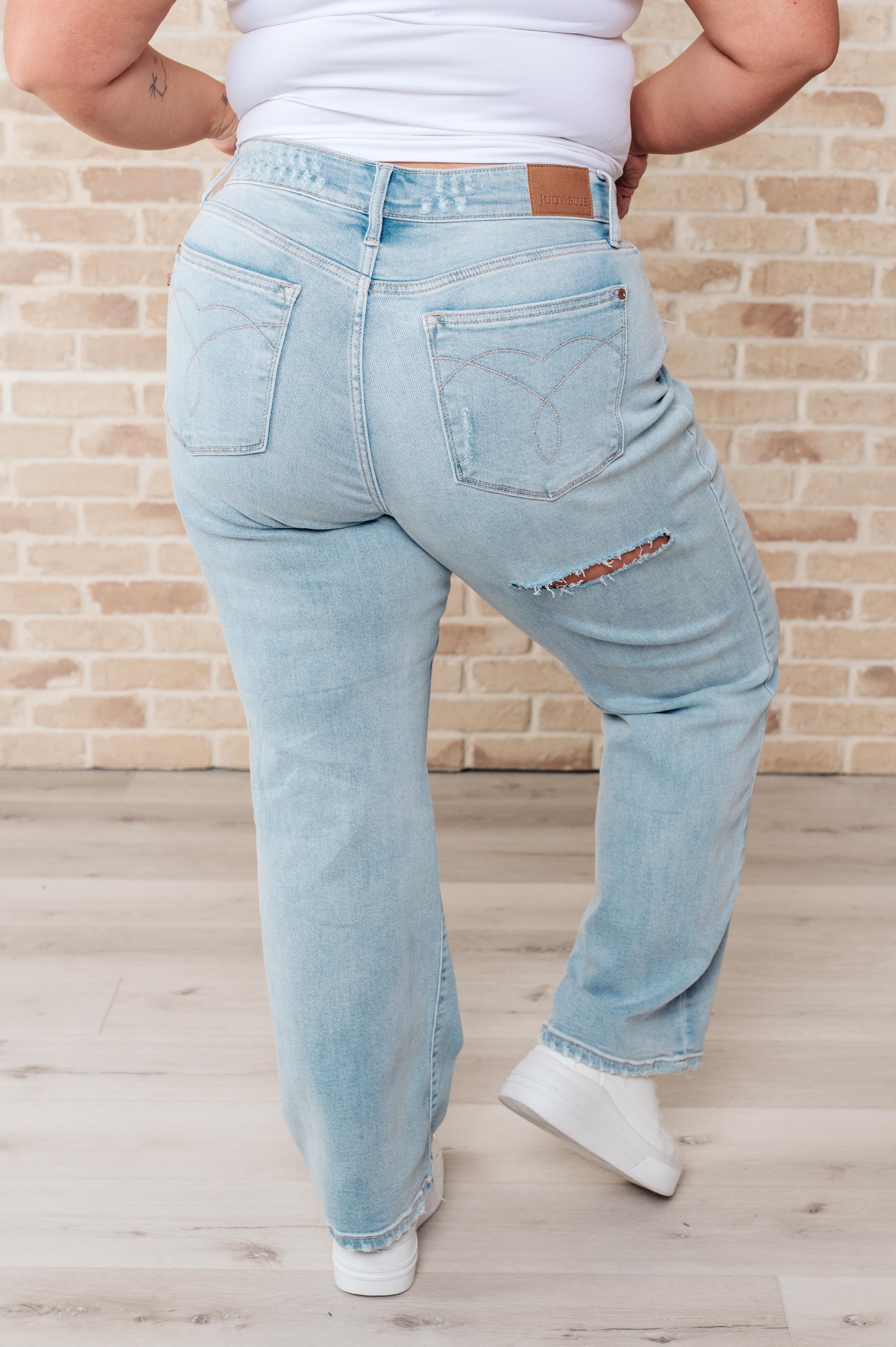 Light wash high-rise jeans with distressed front and back, 90's straight silhouette, and zip fly.