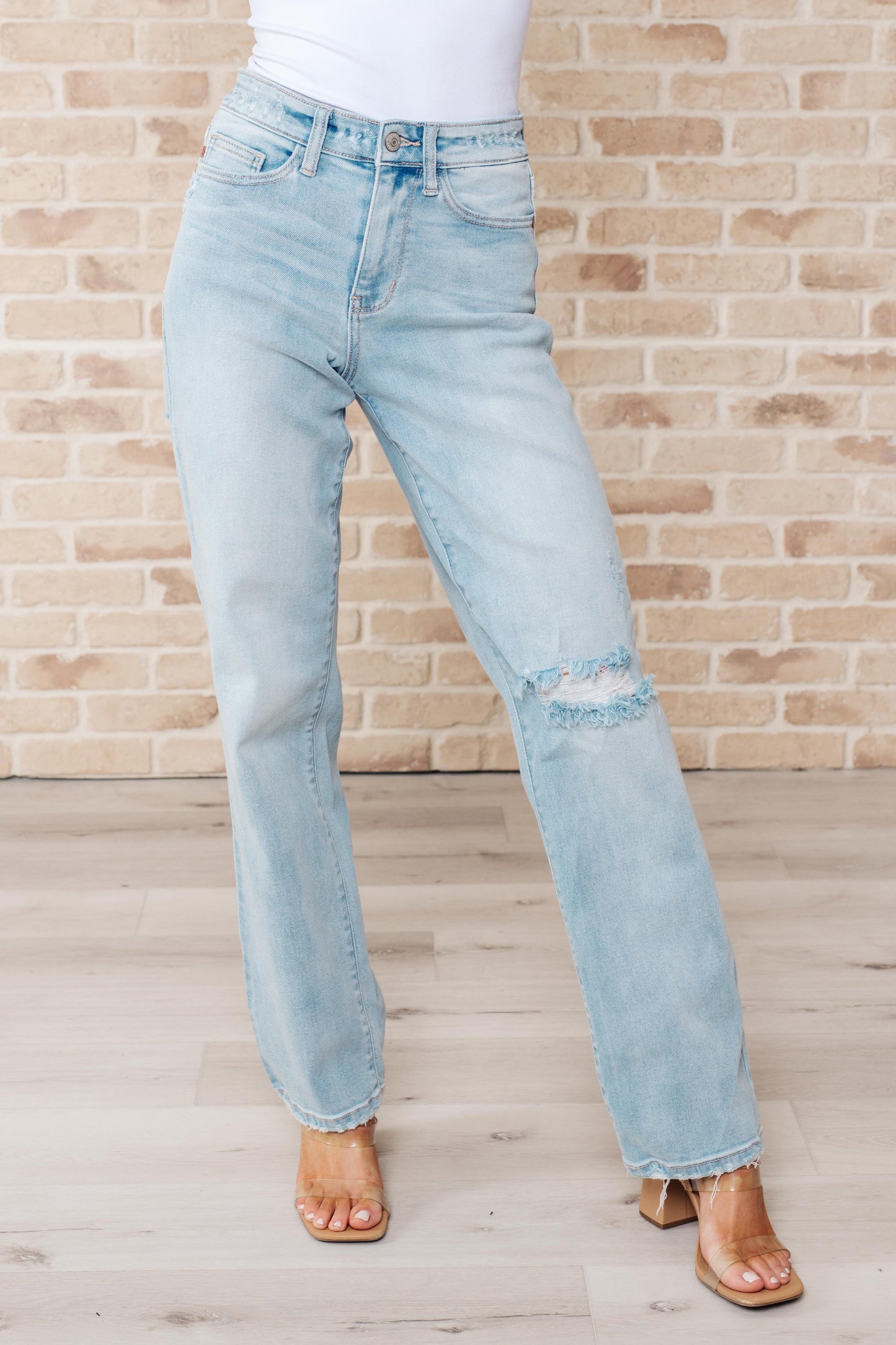 Light wash high-rise jeans with distressed front and back, 90's straight silhouette, and zip fly.