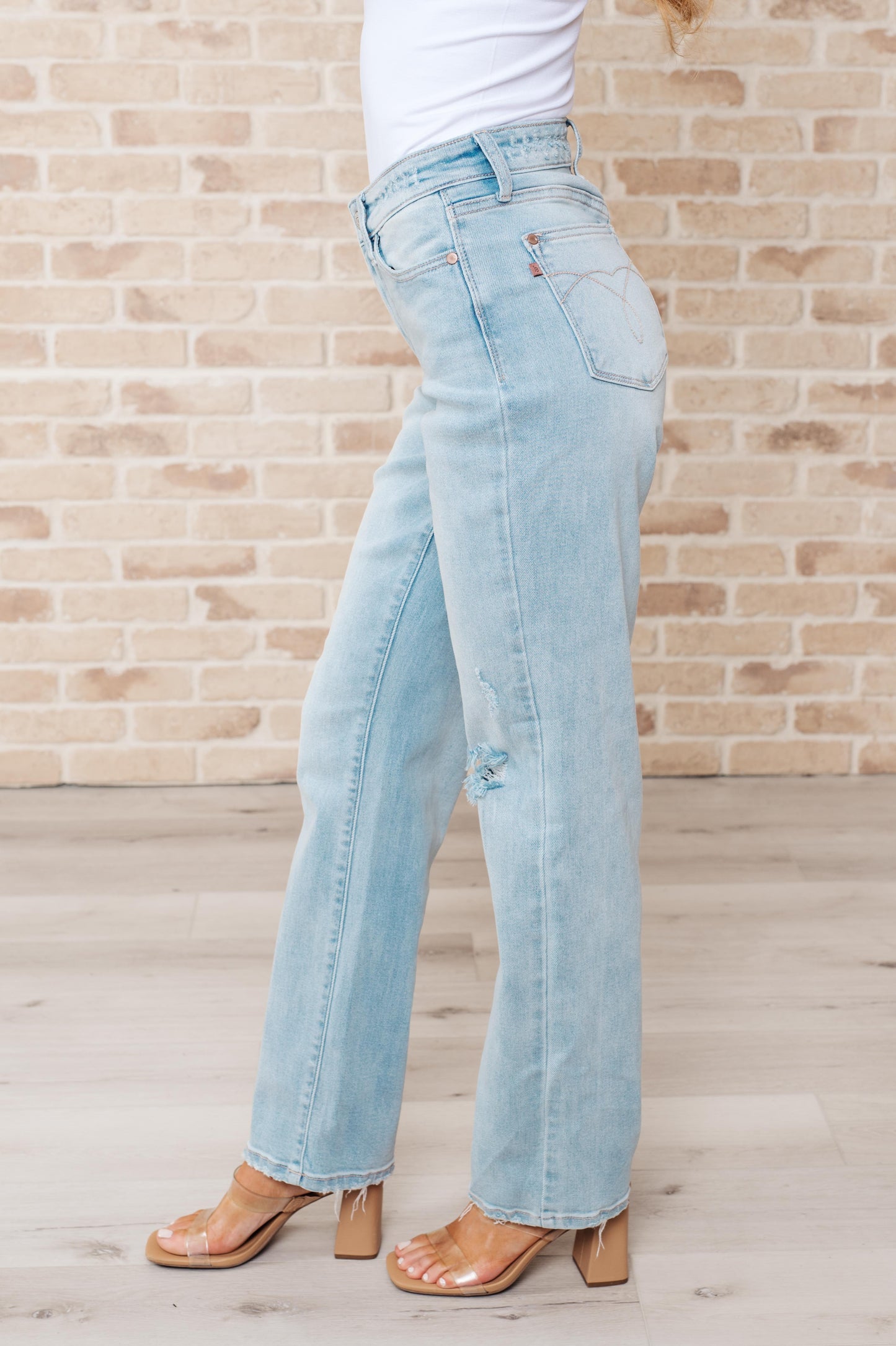 Light wash high-rise jeans with distressed front and back, 90's straight silhouette, and zip fly.