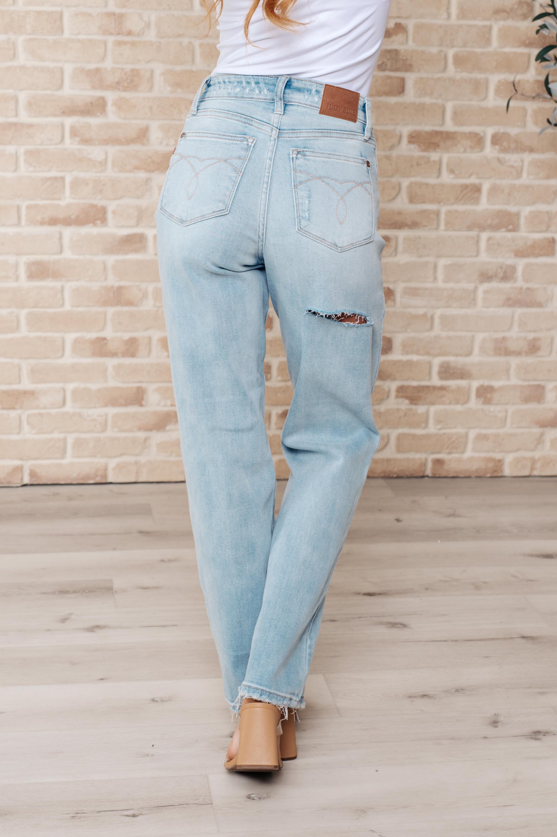 Light wash high-rise jeans with distressed front and back, 90's straight silhouette, and zip fly.