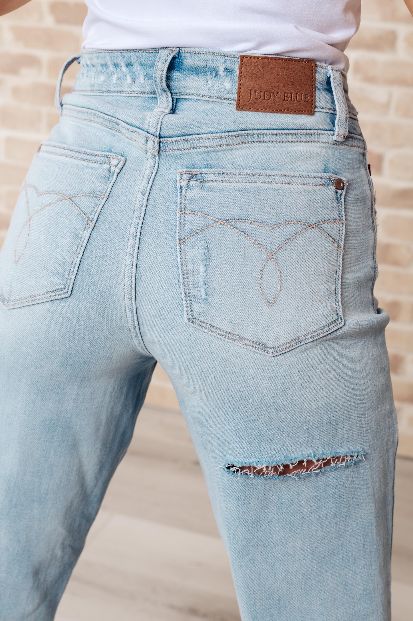 Light wash high-rise jeans with distressed front and back, 90's straight silhouette, and zip fly.