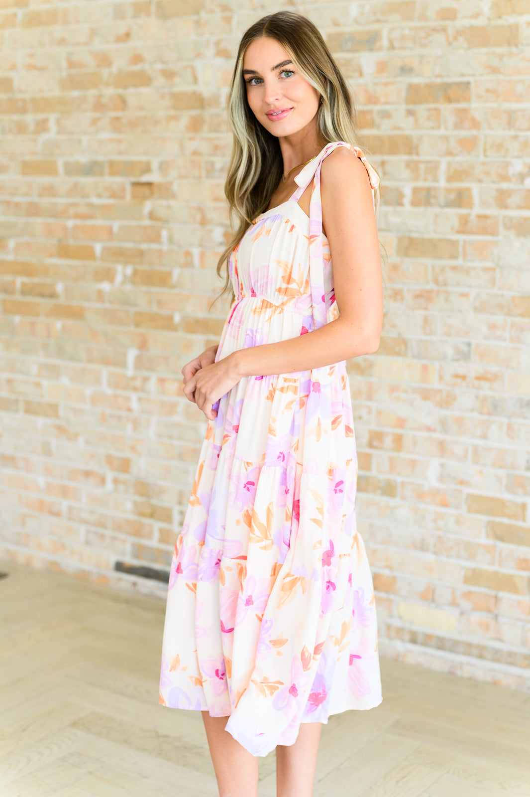 Elegant Pia Pastel Midi Dress featuring sleeveless tie straps, square neckline, and a flowy floral tiered skirt perfect for spring occasions.