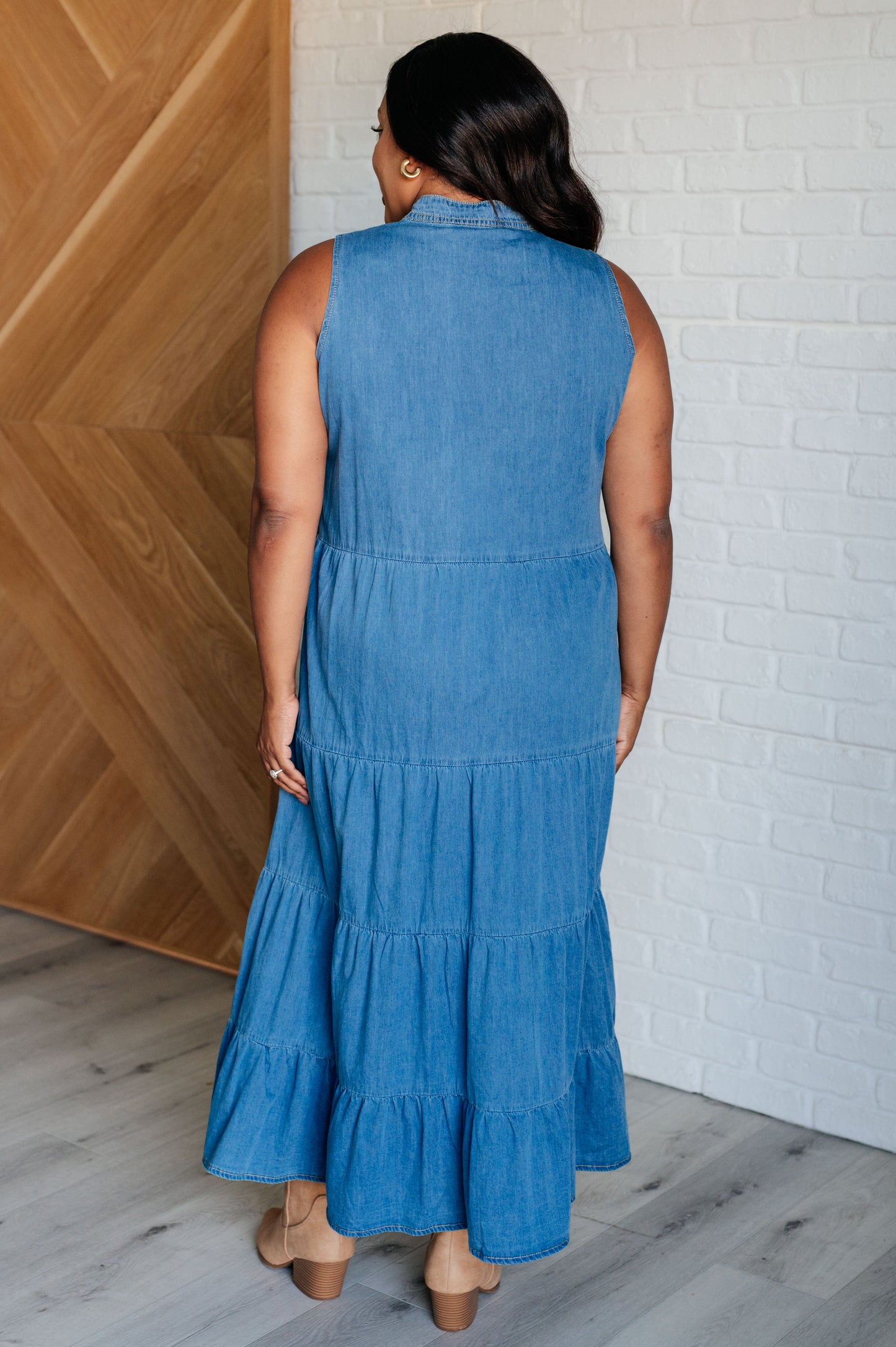 Chambray denim maxi dress featuring a V-neckline with functional neck ties, a tiered skirt, and a sleeveless design. Lightweight and flowy.