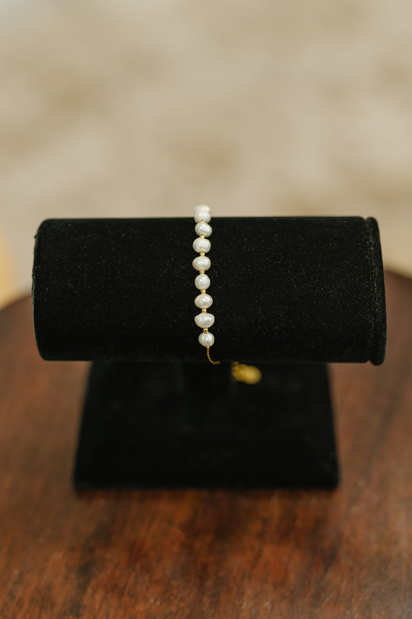 Pretty in Pearls Bracelet displayed on a jewelry stand, highlighting pearl accents and gold chain detail.