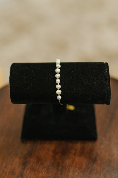 Pretty in Pearls Bracelet displayed on a jewelry stand, highlighting pearl accents and gold chain detail.