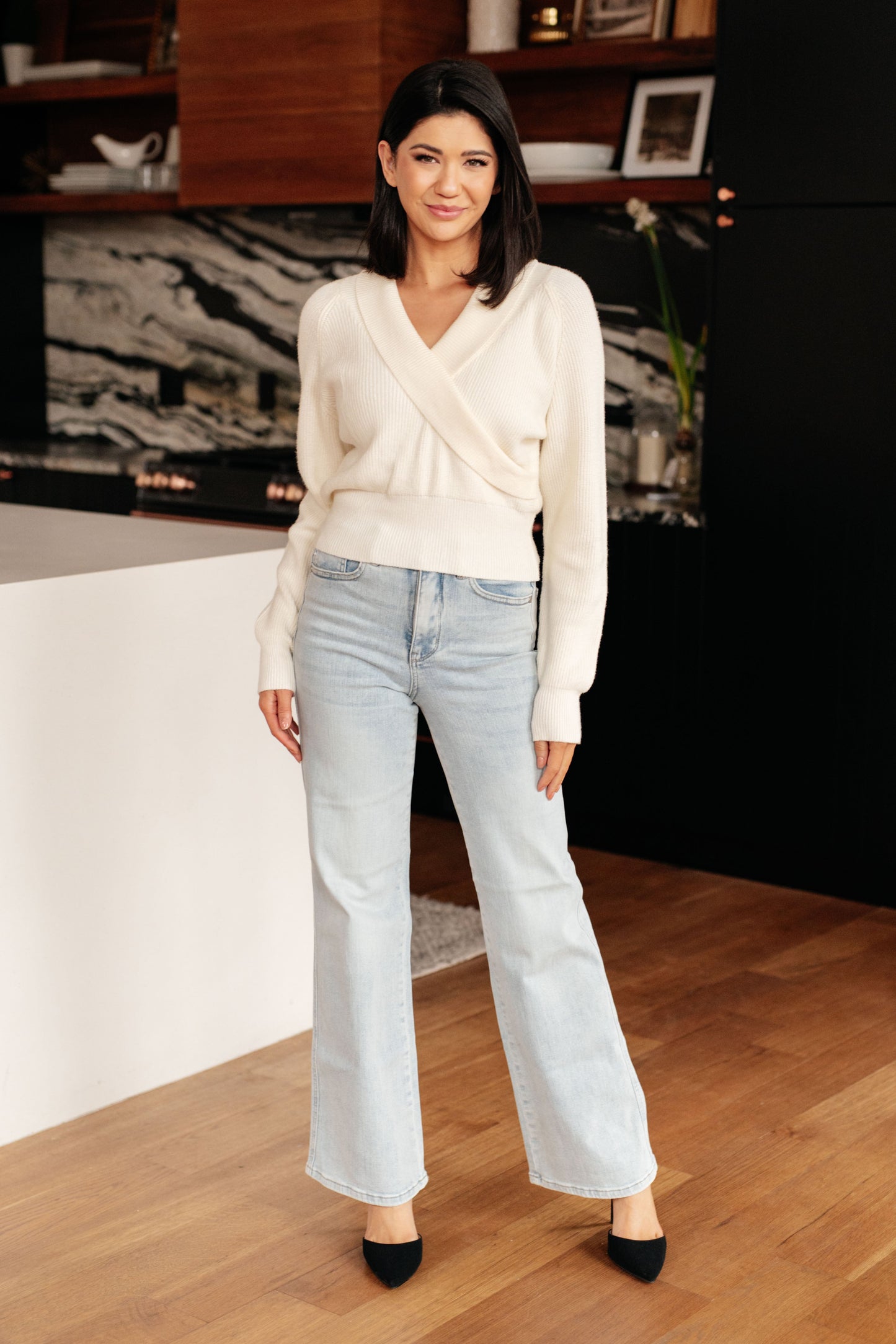 Model wearing Raquel Surplice Crop Sweater in cream with shawl collar and v-neck.