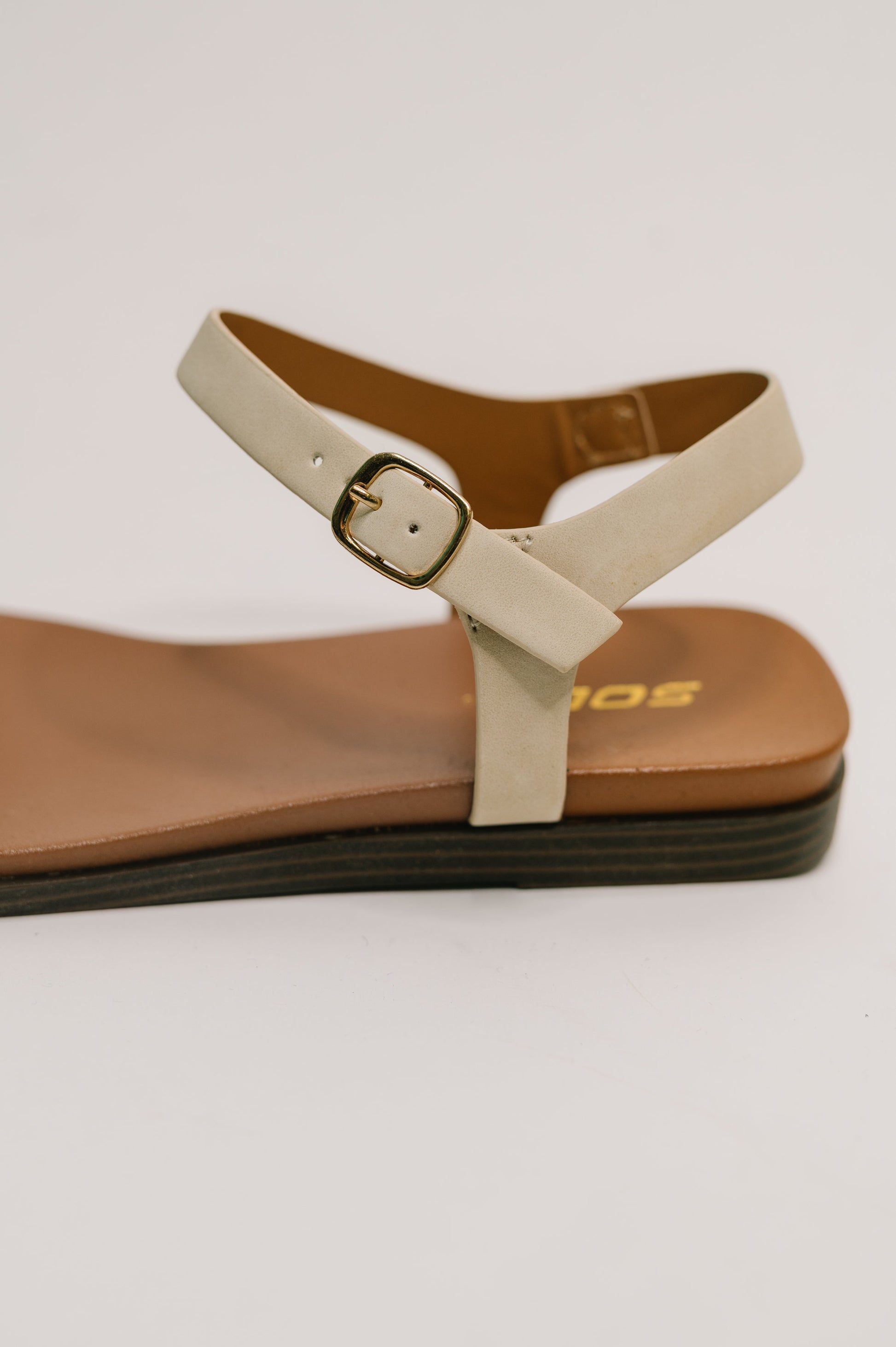 Close up of Riddle Ankle Strap Sandals nubuck texture and gold hardware.