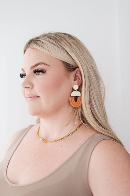 Model wearing Right On Time earrings in beige and orange with bold geometric drop design.