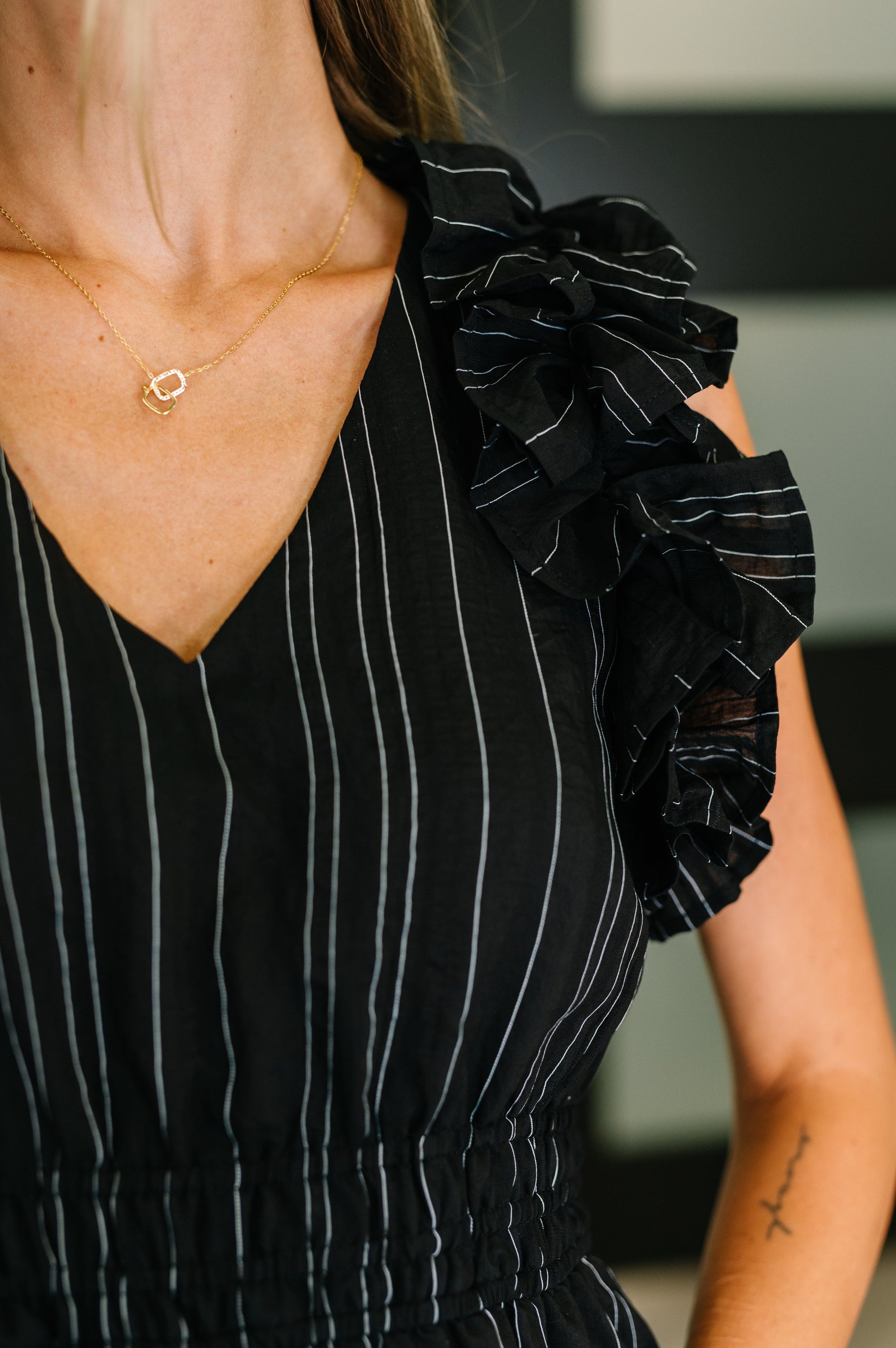 Close up of Romi Pinstripe V-Neck Ruffle Sleeve Dress pinstripe detail and neckline.
