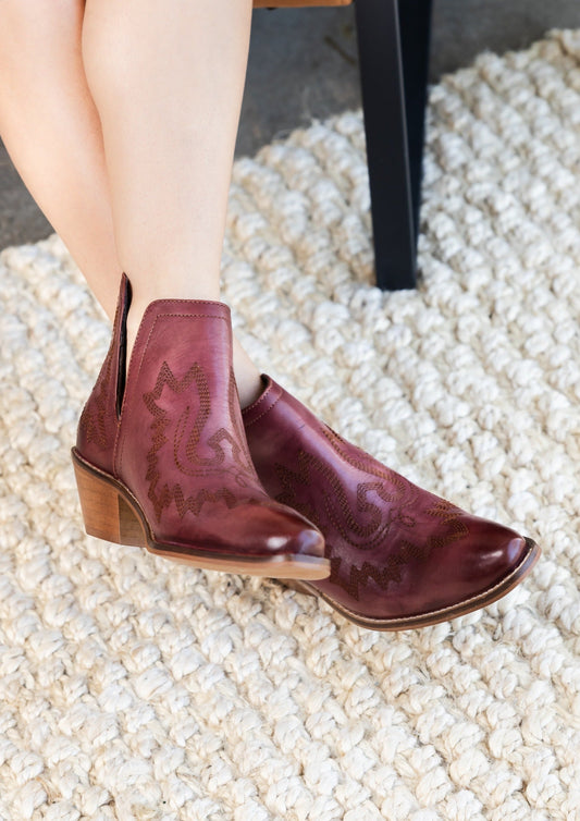 Burgandy leather booties with Western embroidery, roomy snip toe, cushioned footbed, and ankle slits.