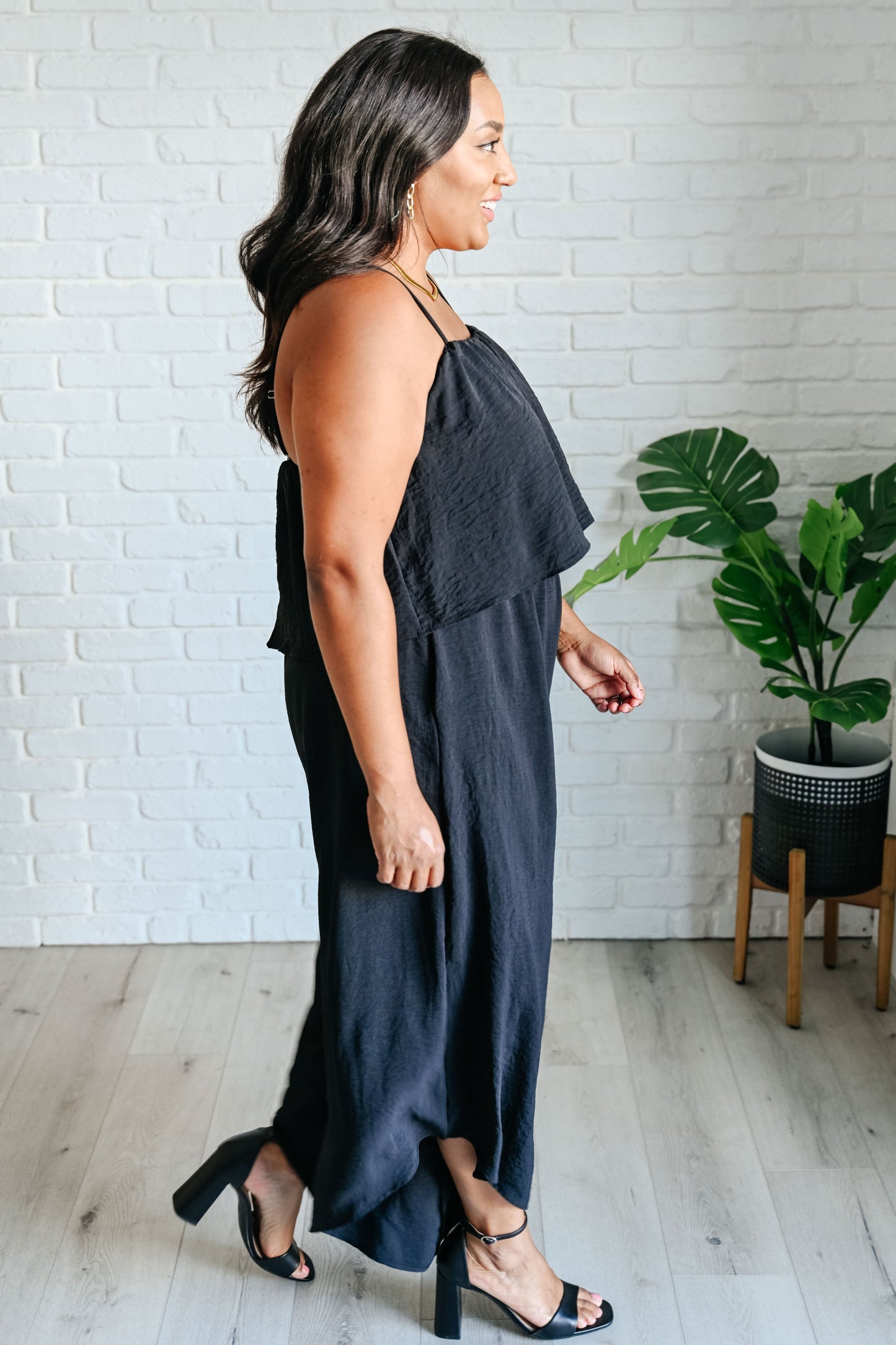 Flattering side view of plus size black jumpsuit with tiered bodice