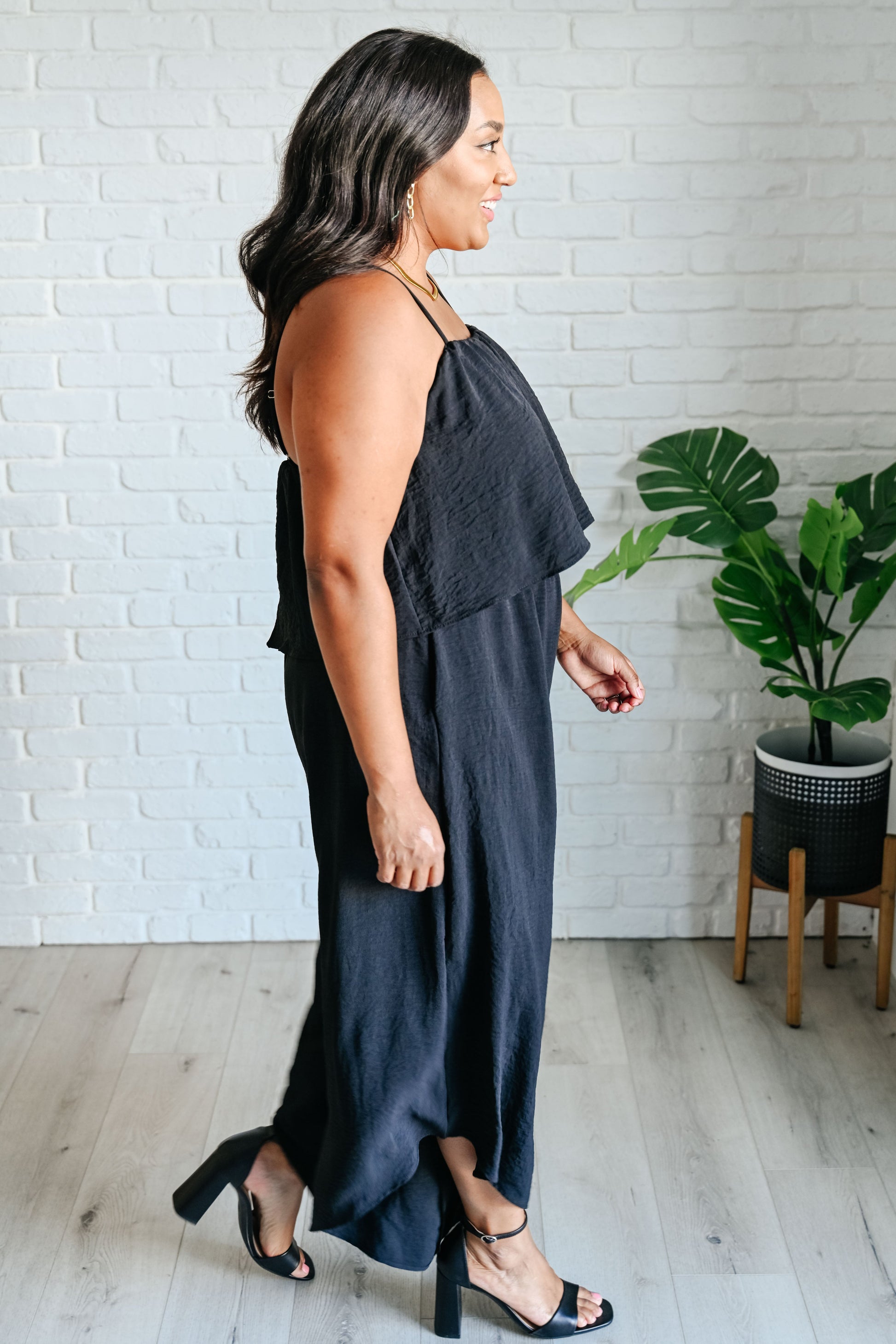Flattering side view of plus size black jumpsuit with tiered bodice