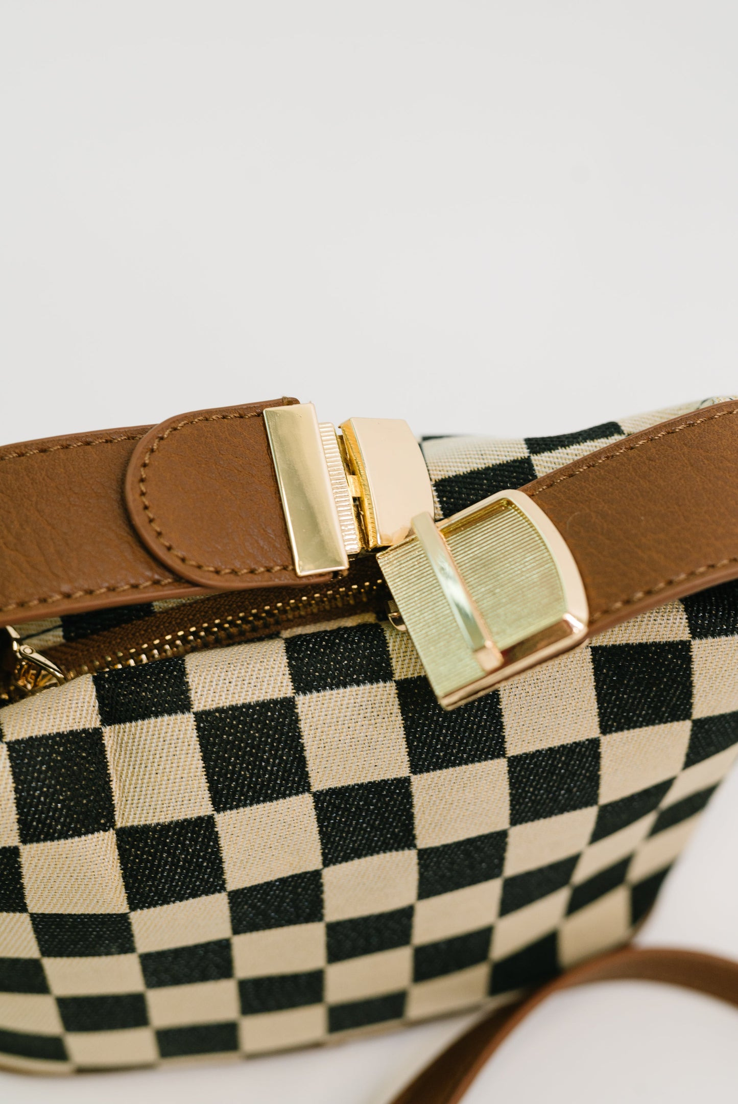 Detail shot of Send a Check Crossbody Bag gold hardware and buckle clip.