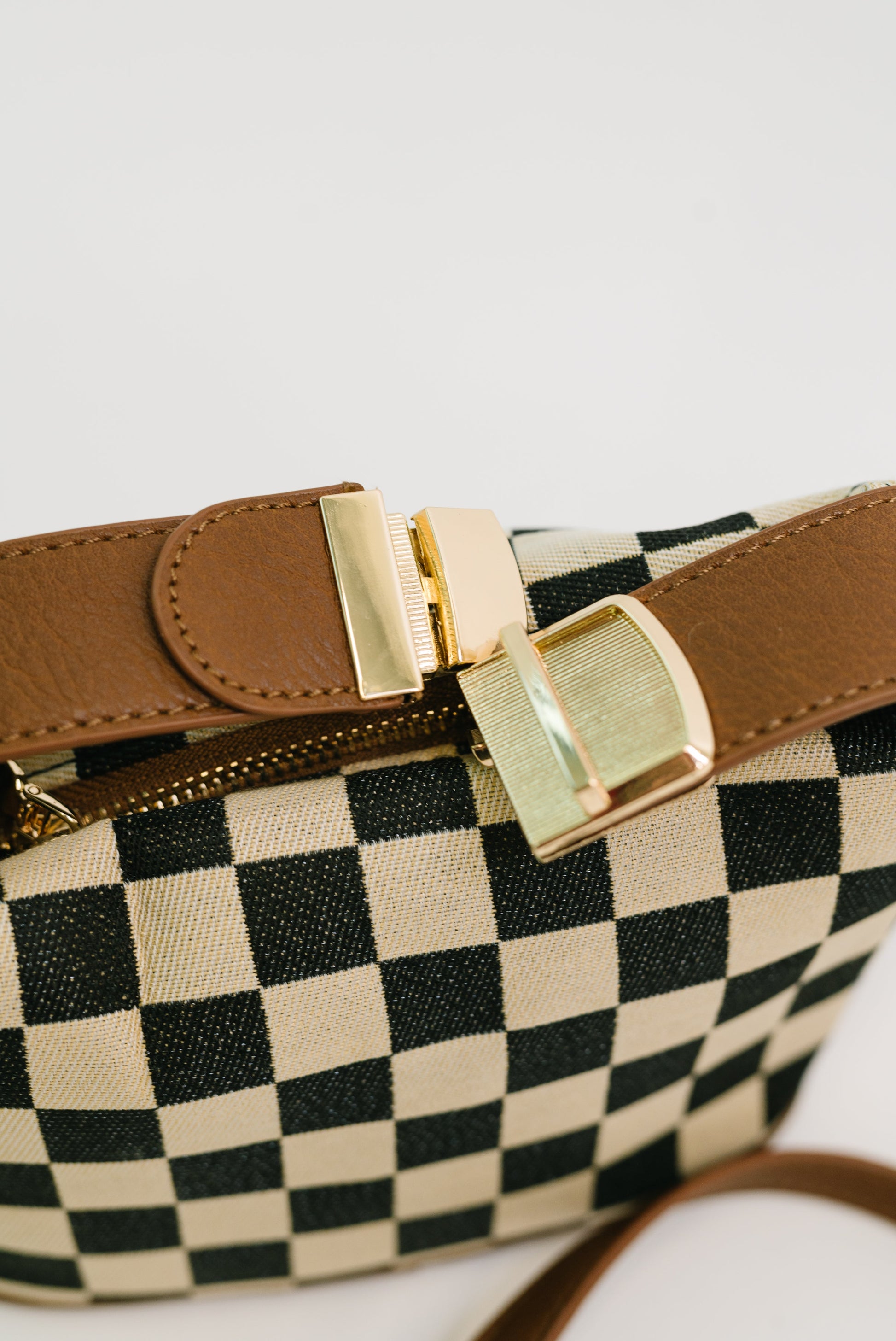Detail shot of Send a Check Crossbody Bag gold hardware and buckle clip.
