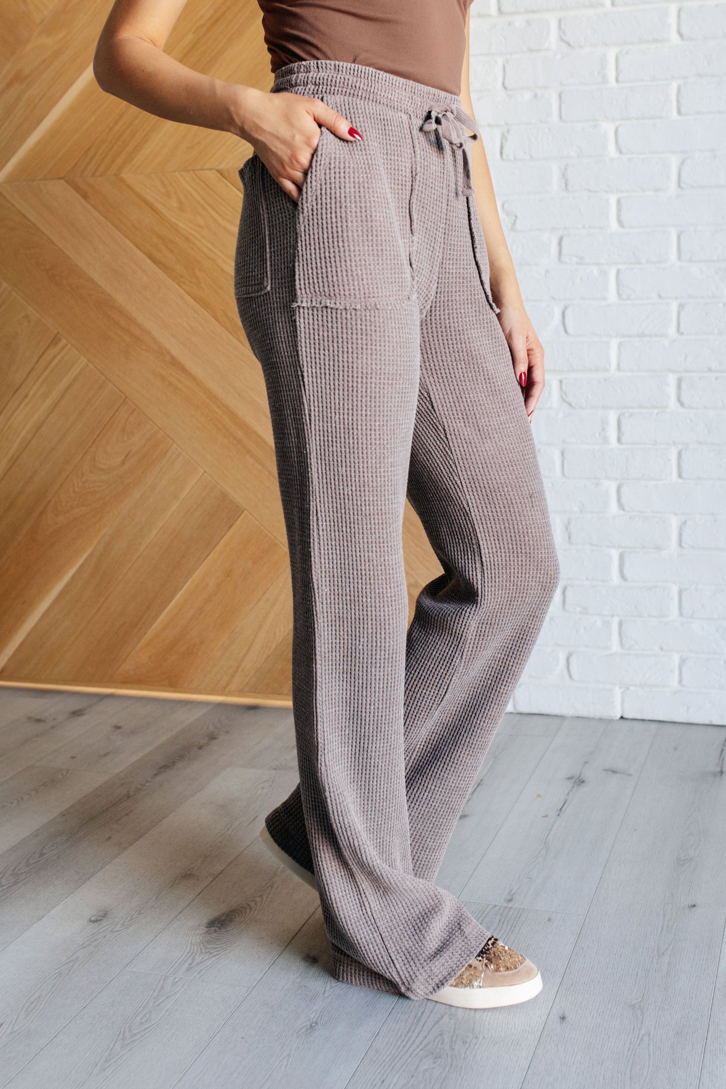 Mineral Wash Waffle Knit Pants in brown featuring a slightly wide leg silhouette, raw edge details, functional side patch pockets, and a cased elastic waistband with drawstring for a cozy, adjustable fit.