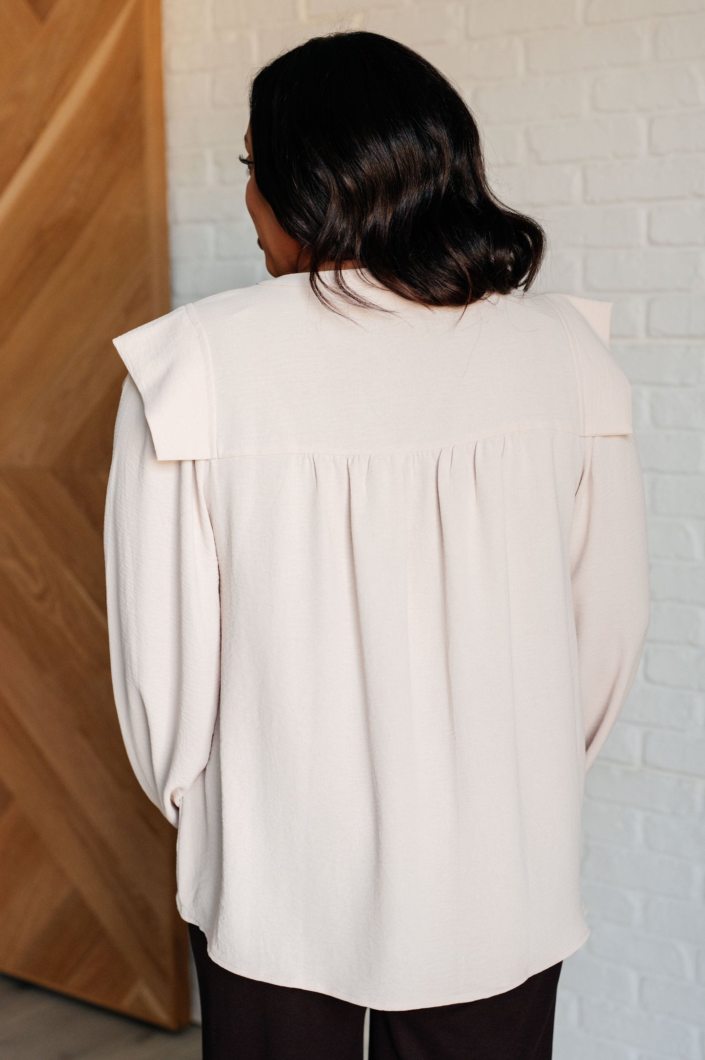 Crinkle woven blouse with a V-neckline, long bishop sleeves, cap shoulders, frilled sleeve cuffs, and gathered details.